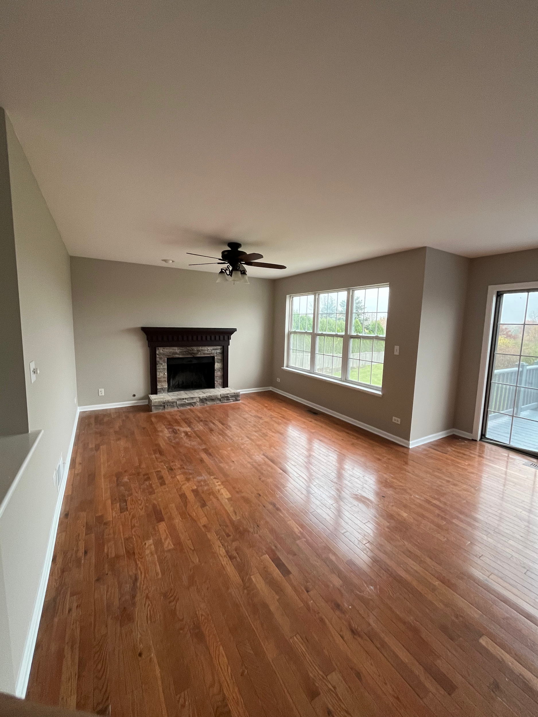 Living room with hardwood floors and trim installed, and beige walls painted.