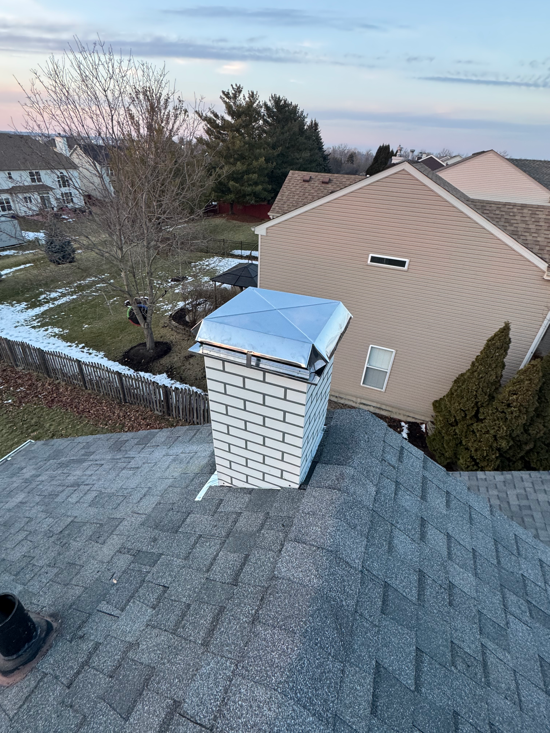 New chimney housing unit installed and bordering shingles replaced