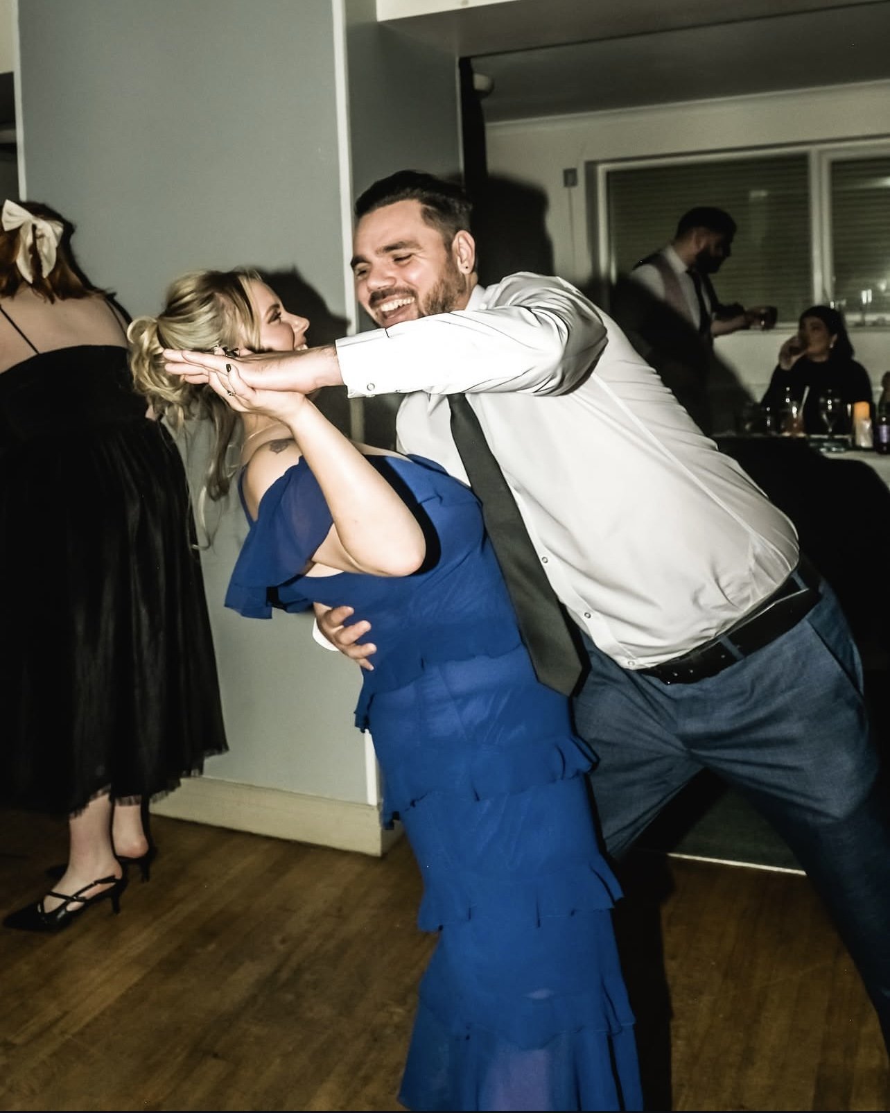 A man and woman dancing and laughing together at a party or celebration.