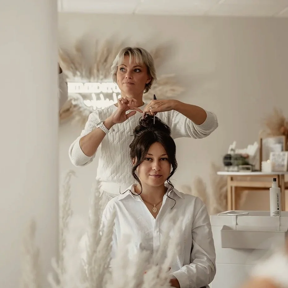 Friseurin stylt eine junge Frau mit dunklen Haaren in einem Salon.