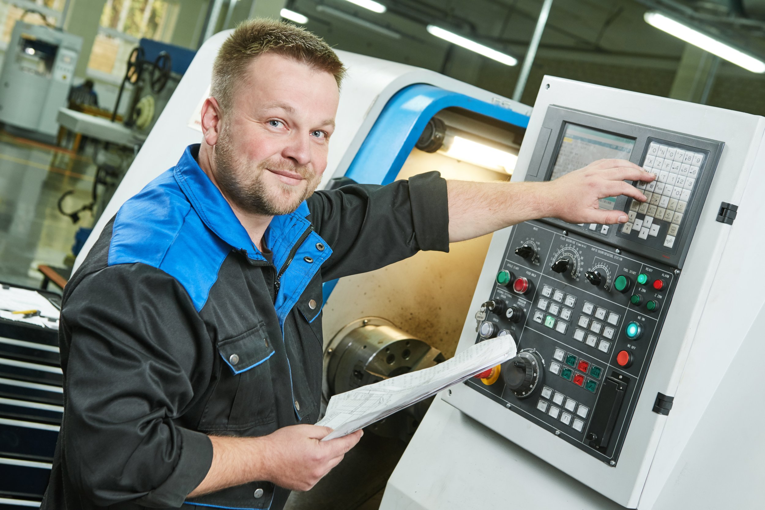 A man operating a CNC machine in an industrial setting.