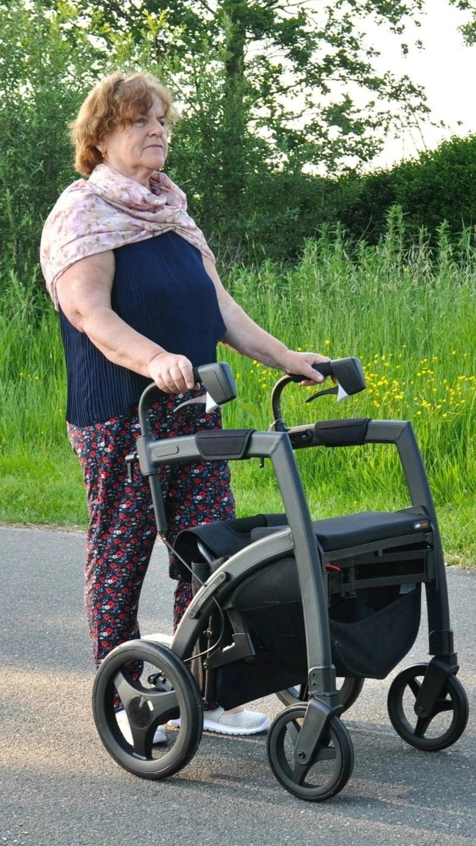 Older lady walking outdoors with her 4 wheeled walker.  Mobility rehabilitation.  Looking strong, confident and healthy
