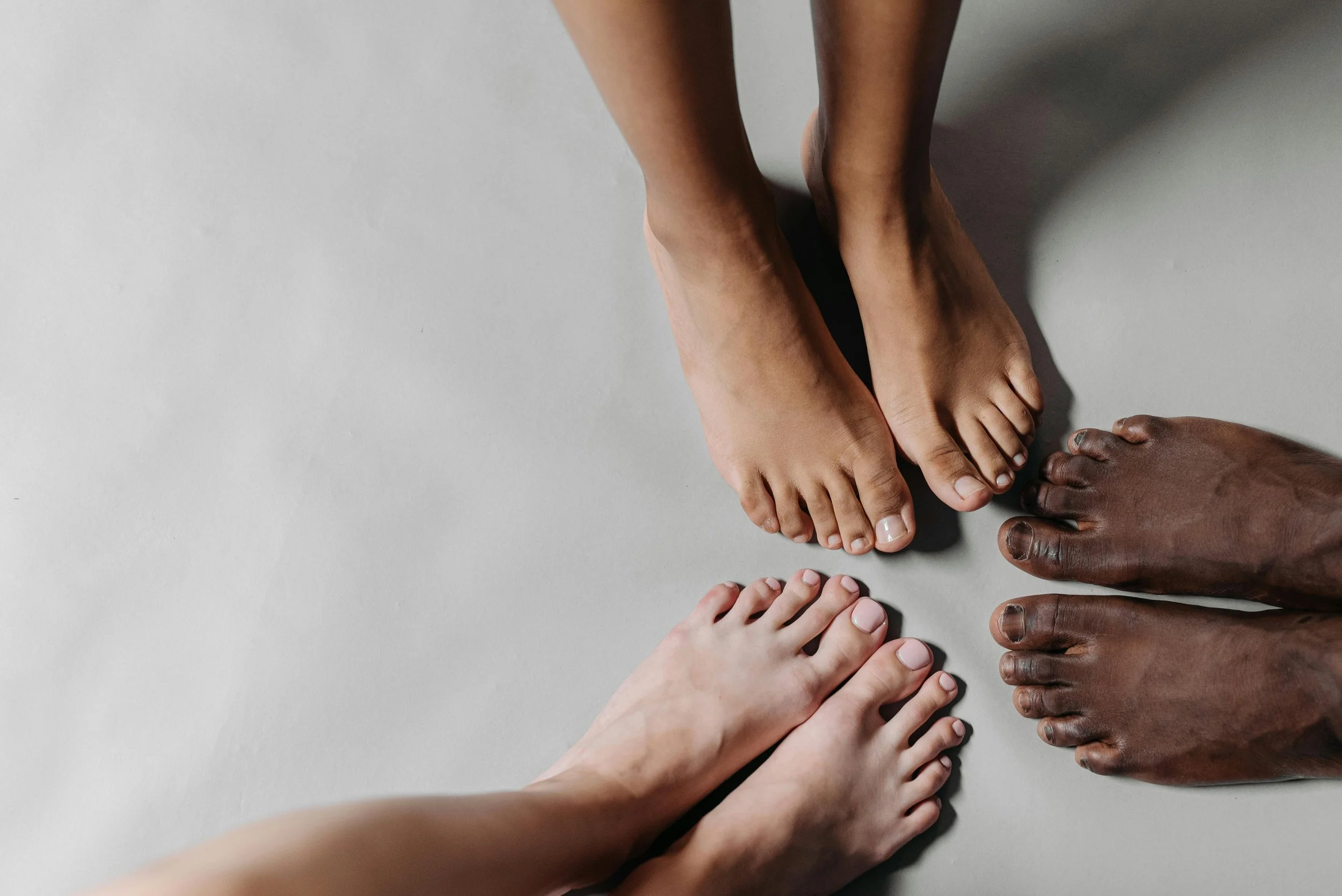 3 pairs of bare feet showing various skin tones.  Advertising foot health and podiatry
