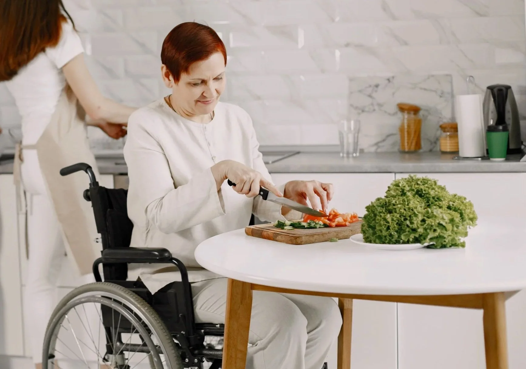 alady who is a wheelchair user is preparing salad.  Independence, life skills