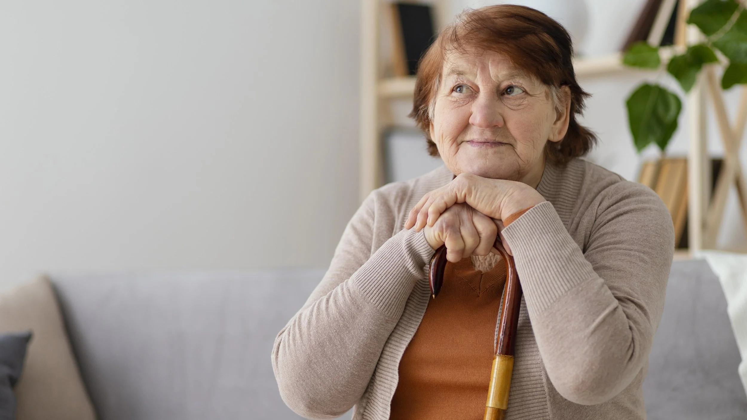 Older Lady sitting with a walking stick.  Occupational Therapy