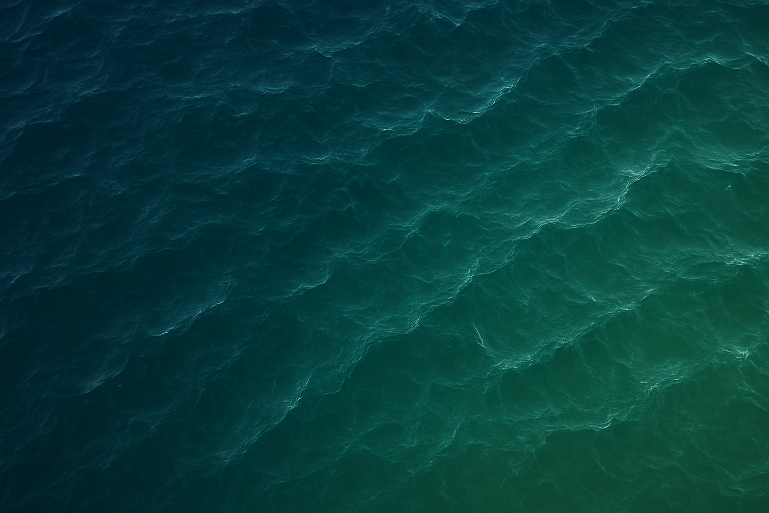 Aerial view of ocean water with blue and green waves