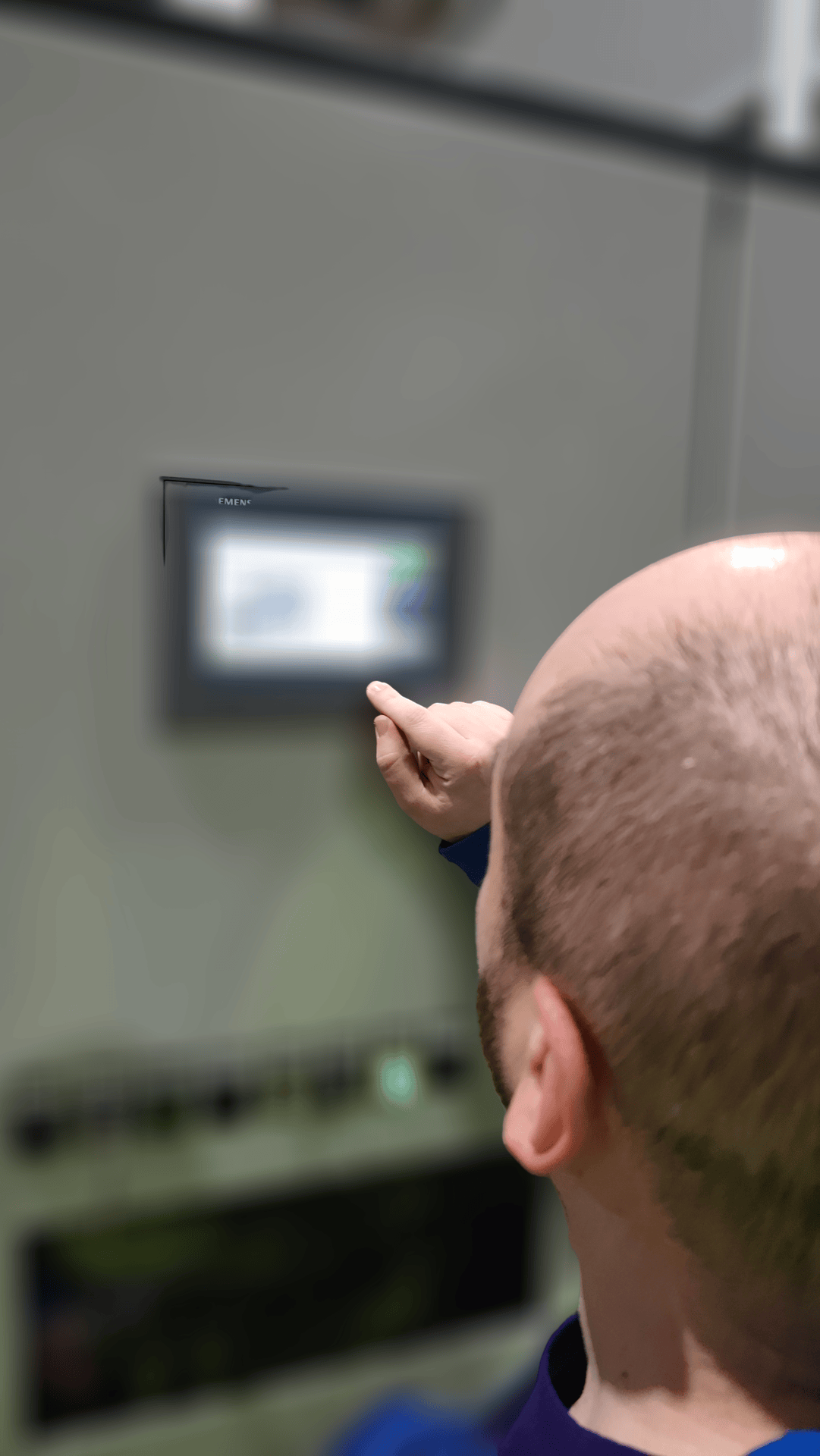 Uomo che utilizza un pannello di controllo o touchscreen PLC su una parete grigia