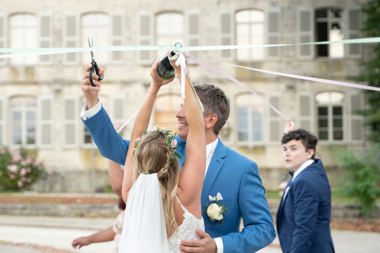 Activité durant le vin d'honneur, le jeu du ruban avec une bouteille de champagne et les mariés qui s'amusent ! Lorraine - 2021. Par Viviane Eyer, Photographe de mariage dans le Grand Est