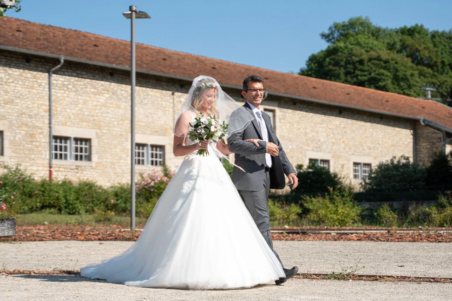 La mariée fait son entrée au bras de son père. Par Viviane Eyer, Photographe de mariage dans le Grand Est.
