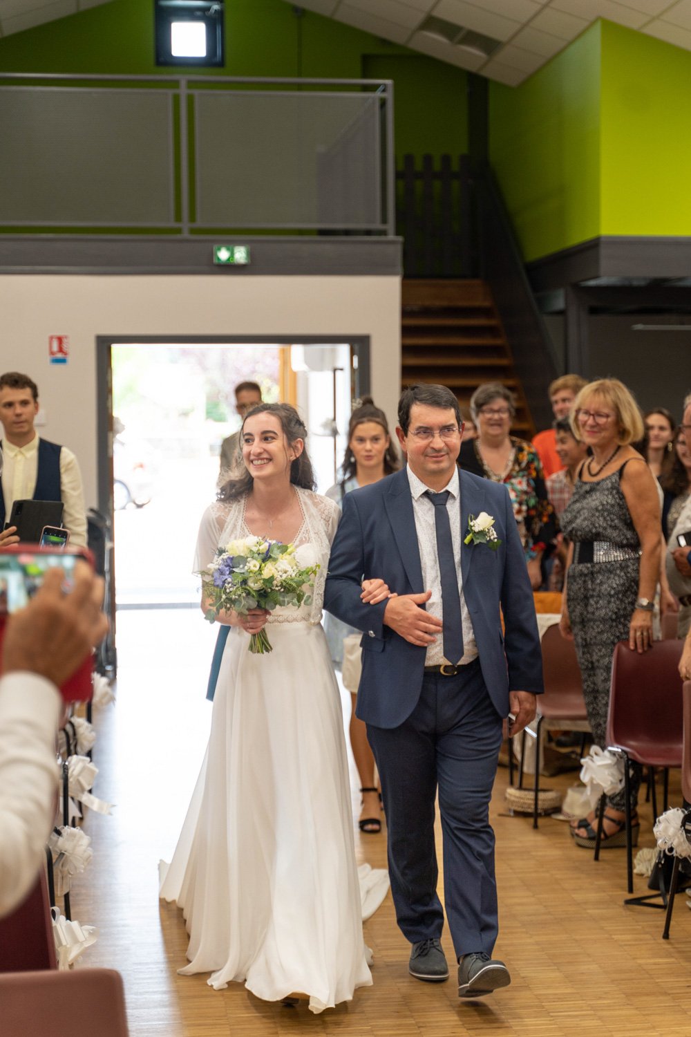 Entrée de la mariée avec son père. Jura - 2022. Par Viviane Eyer, Photographe de mariage dans le Grand Est, la Bourgogne etc...