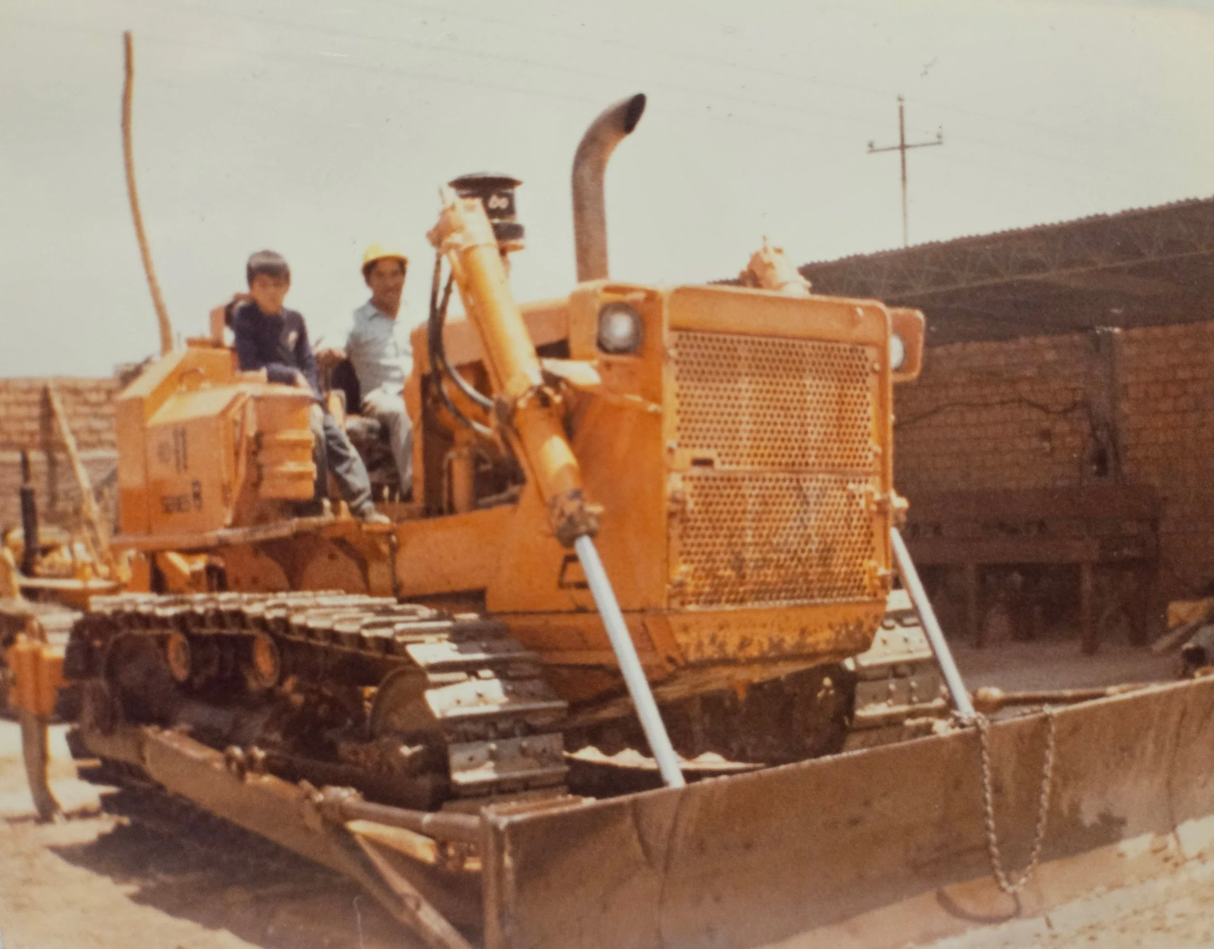 Niños en un tractor de color naranja en un área de construcción o campo