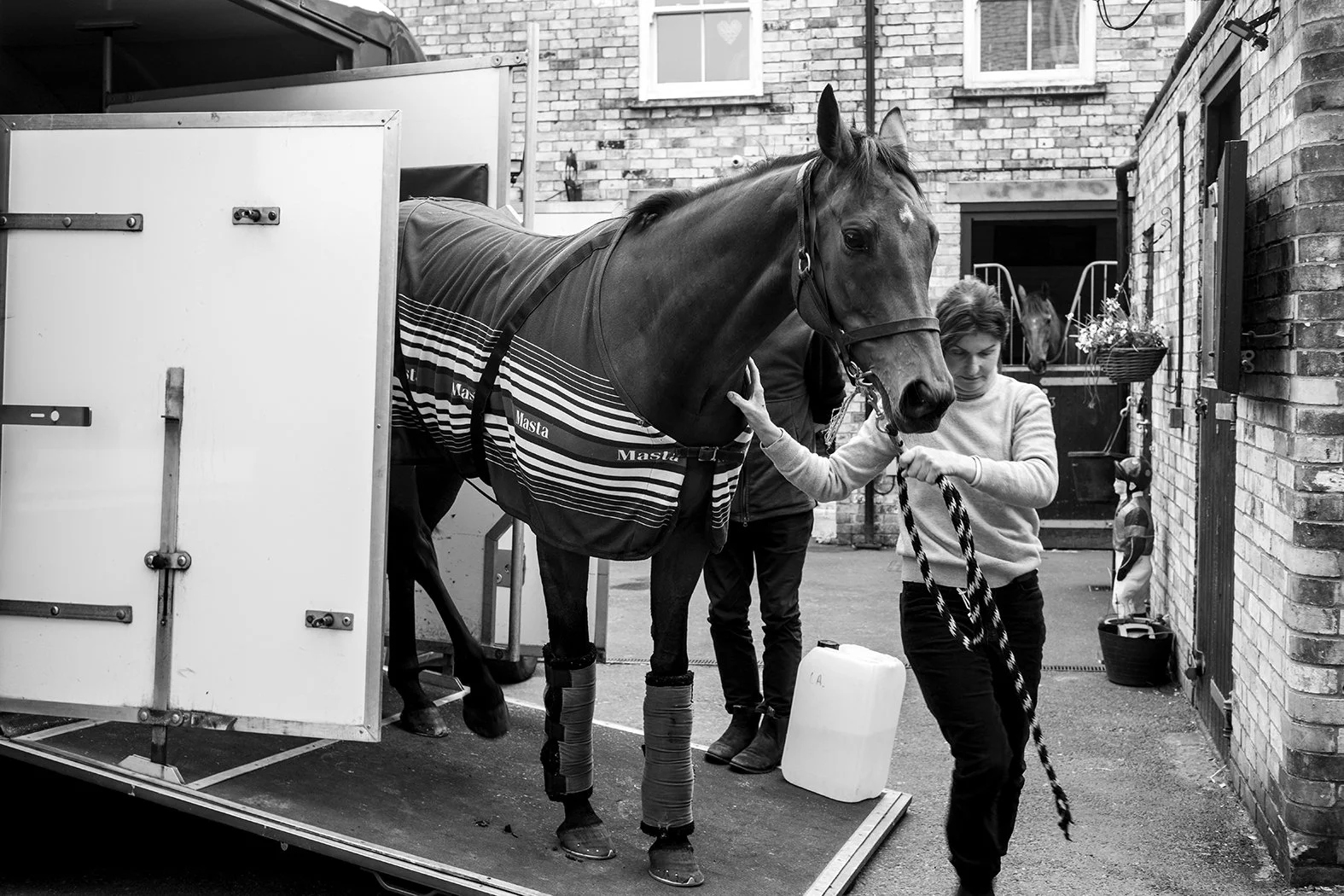 A woman and a man tending to a horse inside a stable or garage.