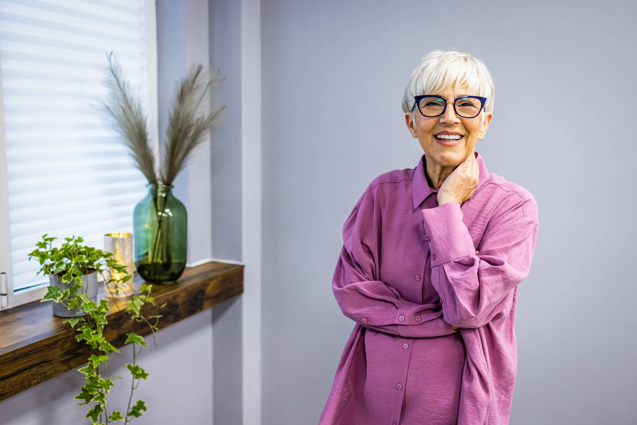 An older woman with short hair and black-rimmed glasses smiling with her new crown