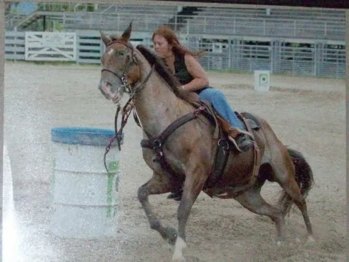 Dental assistant, Debby, riding a horse around an obstacle in a riding arena during daytime.