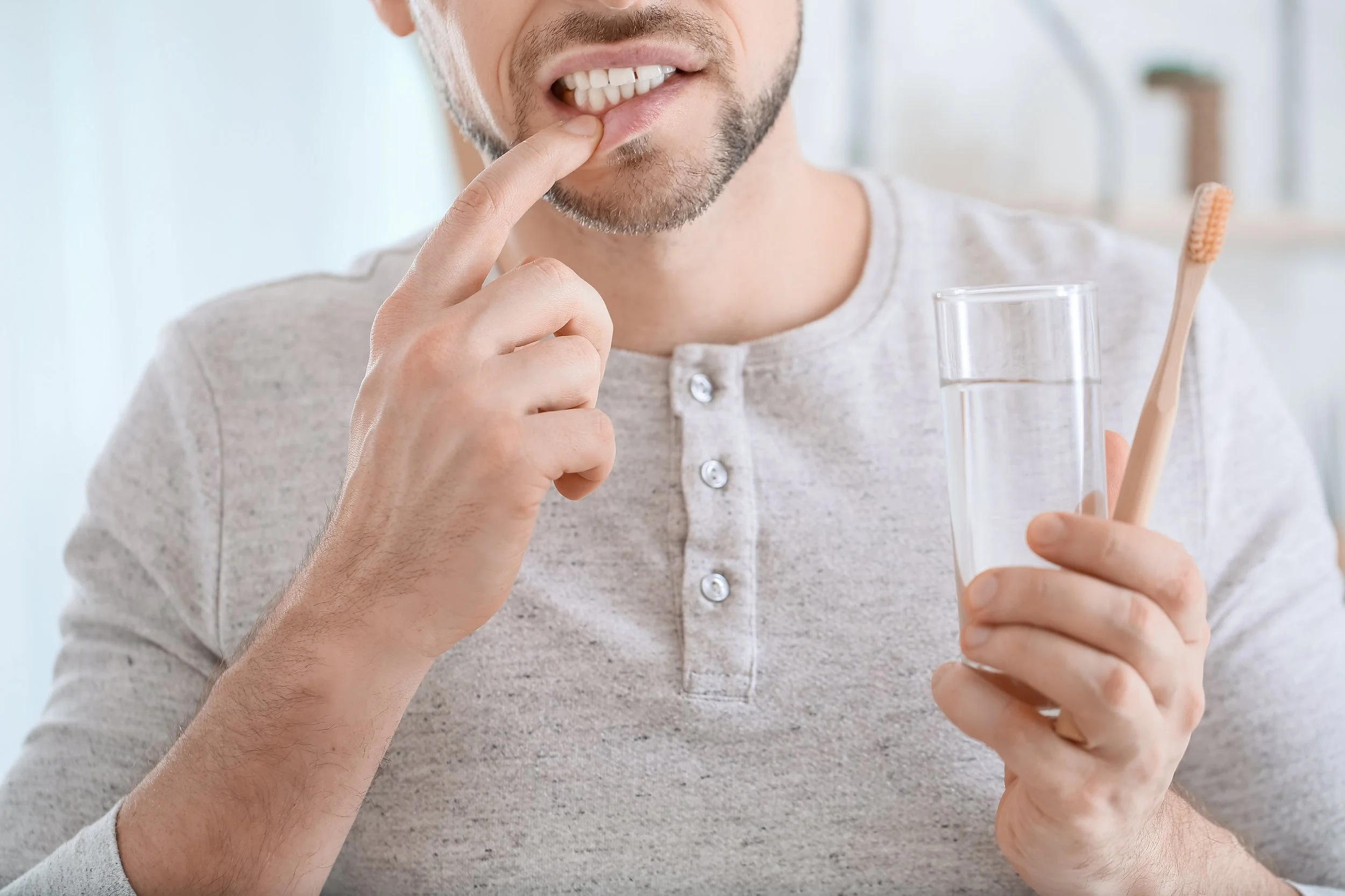 a man in pain while brushing his teeth