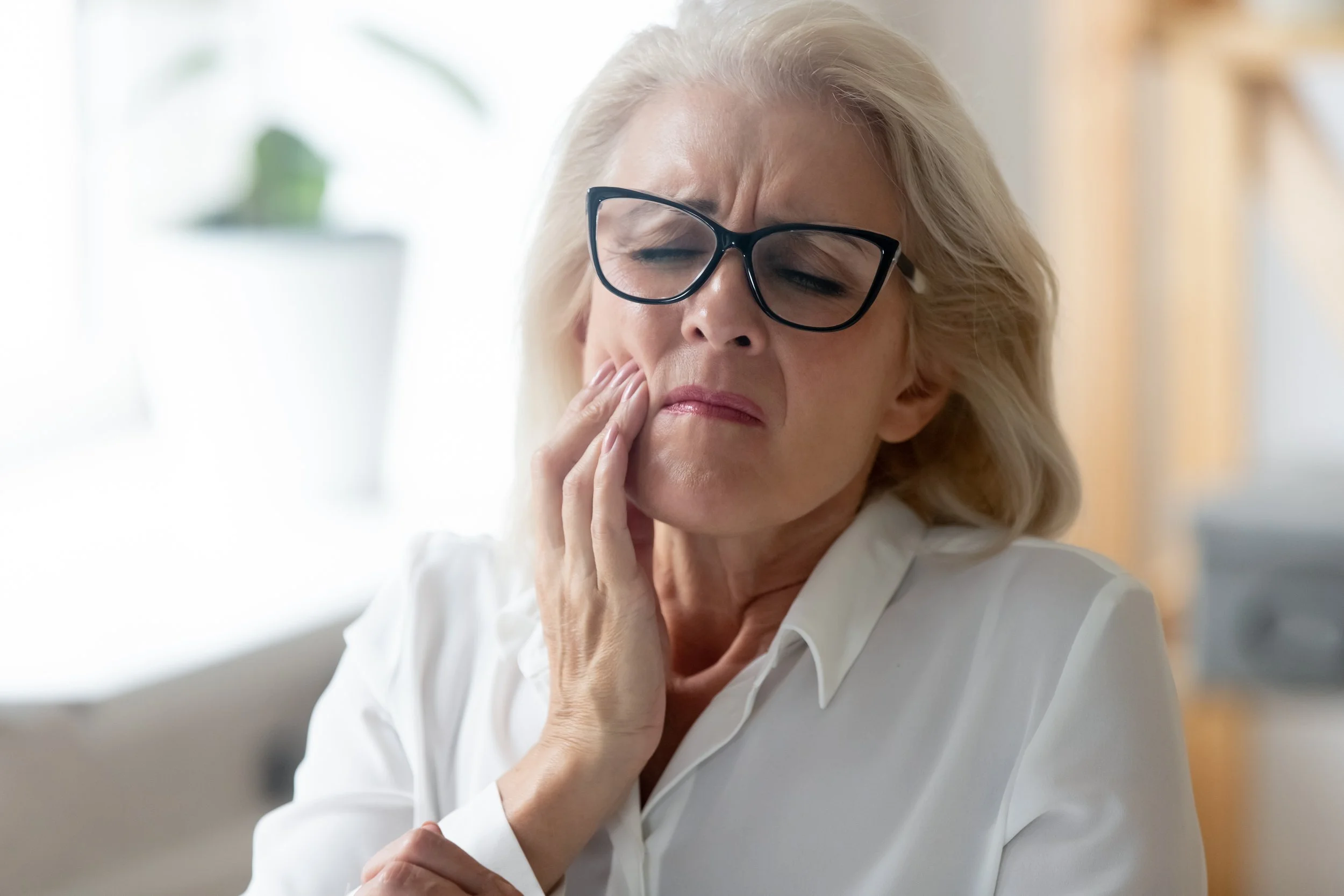 an older woman with tooth pain holding her cheek