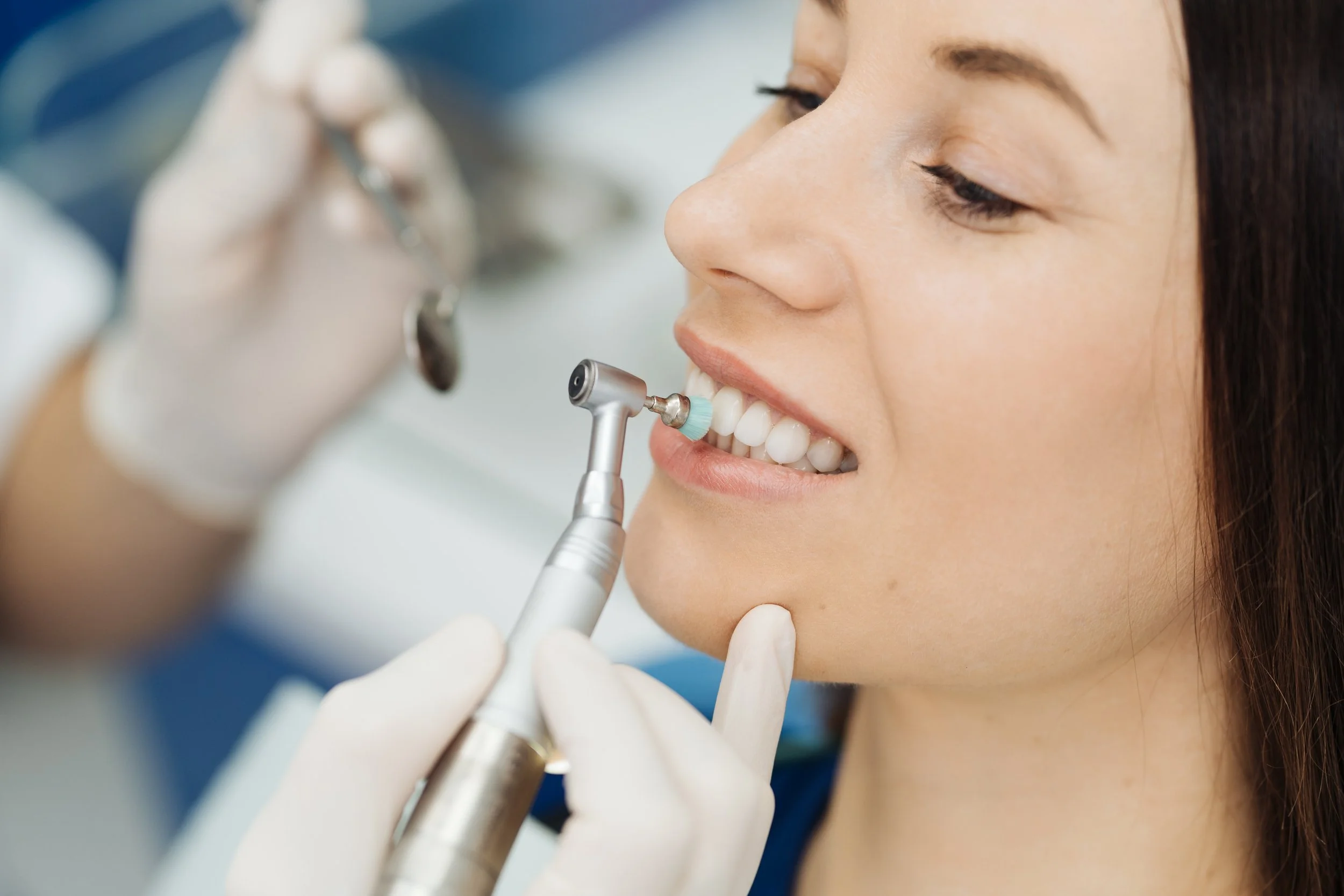 a woman sitting down while her teeth are being polished