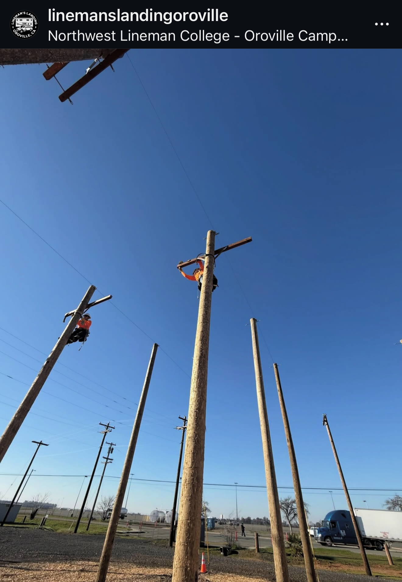 Workers installing or repairing electrical utility poles in an outdoor area with a clear blue sky.