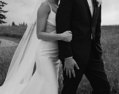 A bride and groom holding hands outdoors, in a black and white photo.
