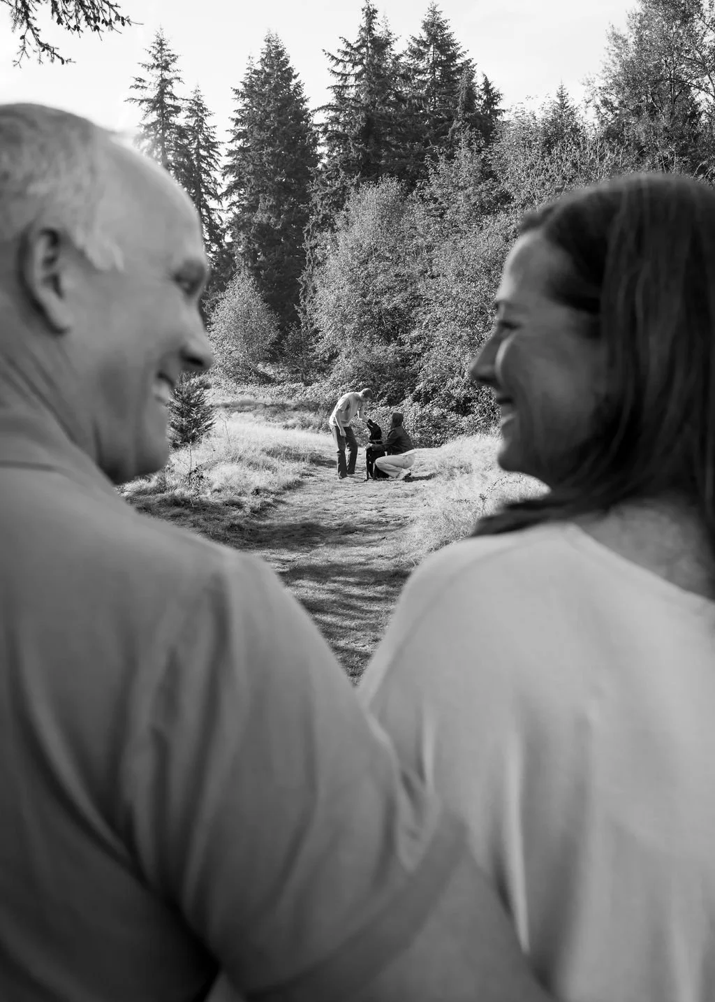 Black and white documentary family portrait of parents walking together along a forest path near Seattle