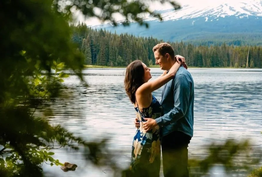 Couple embracing beside a mountain lake in the Pacific Northwest, photographed in a quiet and intimate outdoor setting of Lake Trillium, Oregon