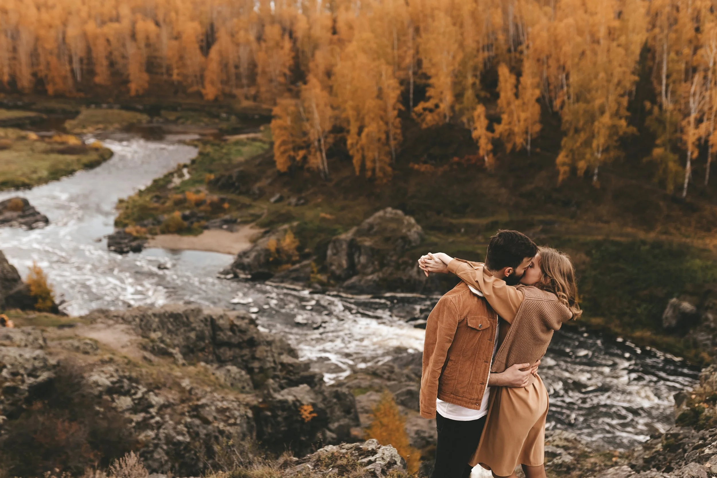 Couple embracing beside a river in the Pacific Northwest during autumn, photographed in a natural and editorial style