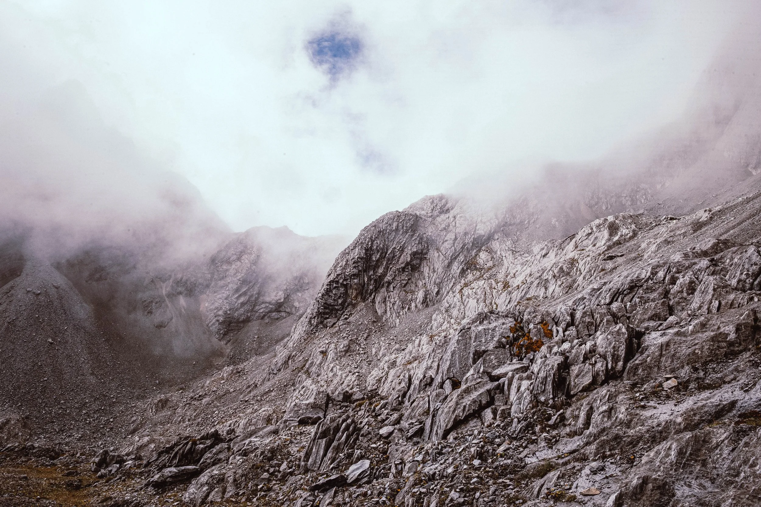 Grote rotsachtige berg met mist en bewolking in een berglandschap.