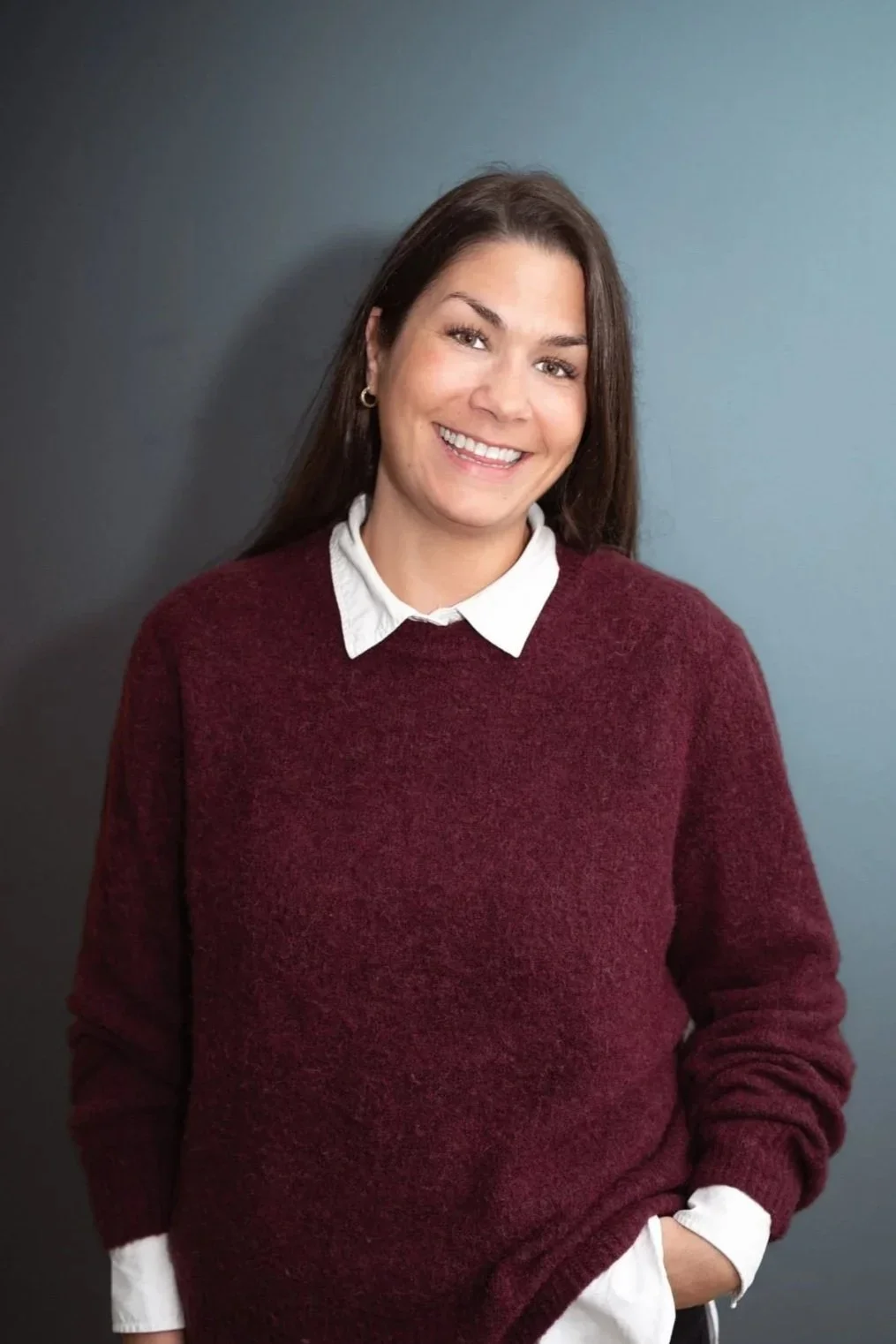 Photo of dark haired woman in a red jumper smiling at the camera; Benedicte Christie Knudtzen in a red