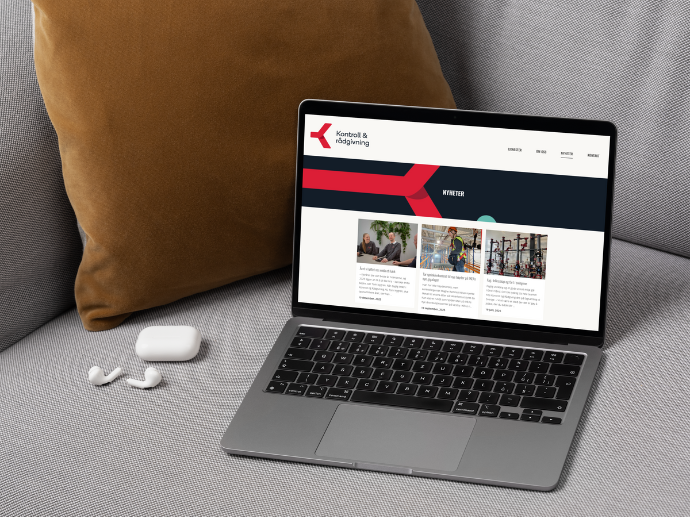 A laptop sitting on a grey couch with a brown pillow behind it. A website is on the screen.