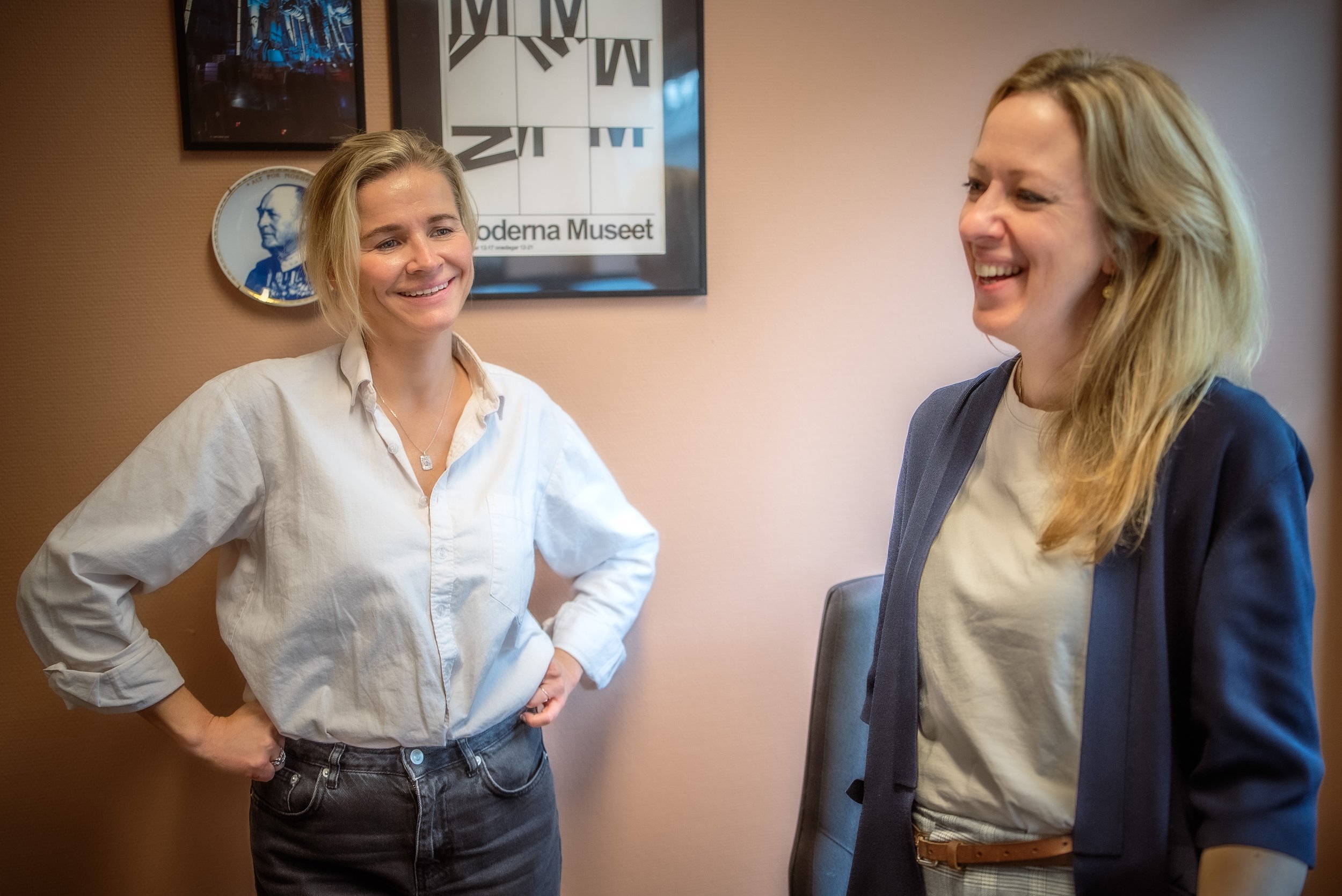 Two mwomen standing in the office of Skippertak, smiling and laughing