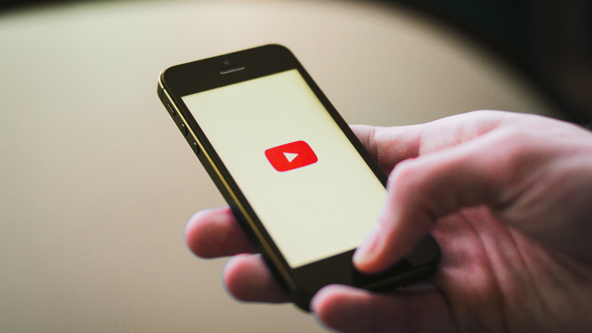 Persoon houdt een smartphone vast met het YouTube-logo op het scherm in podcast omgeving.