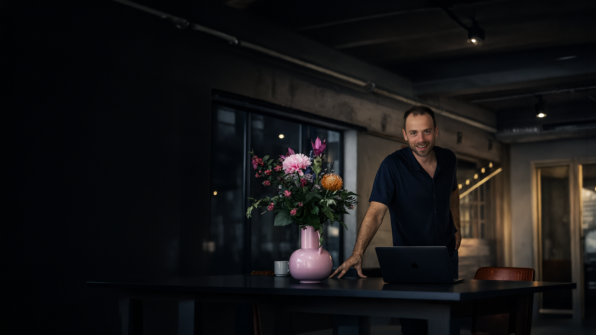 Strateeg van Voxtudio aan bureau met open laptop in podcaststudio