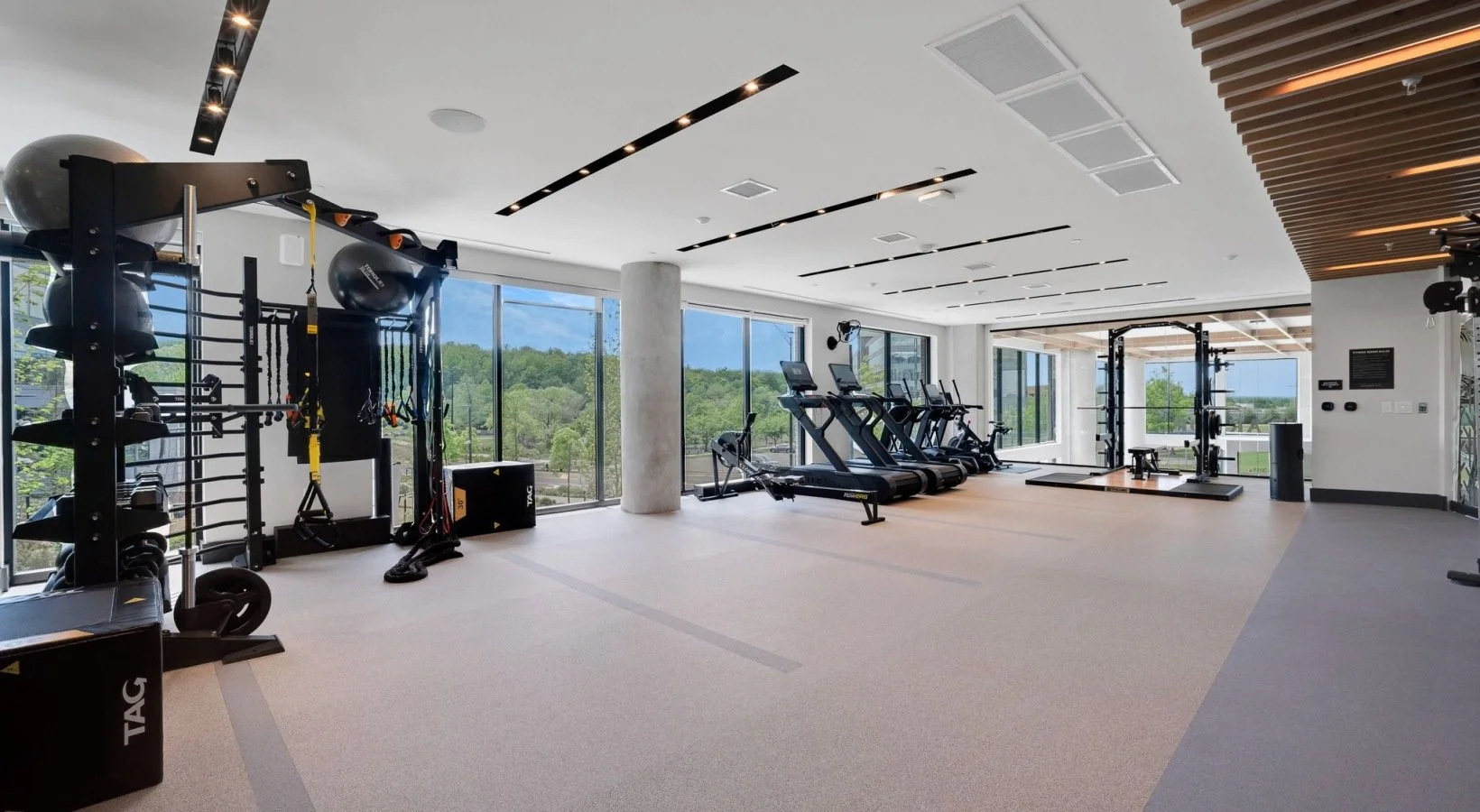 Modern private gym in Reston, VA featuring cardio machines, weightlifting equipment, TRX straps, and a power rack.