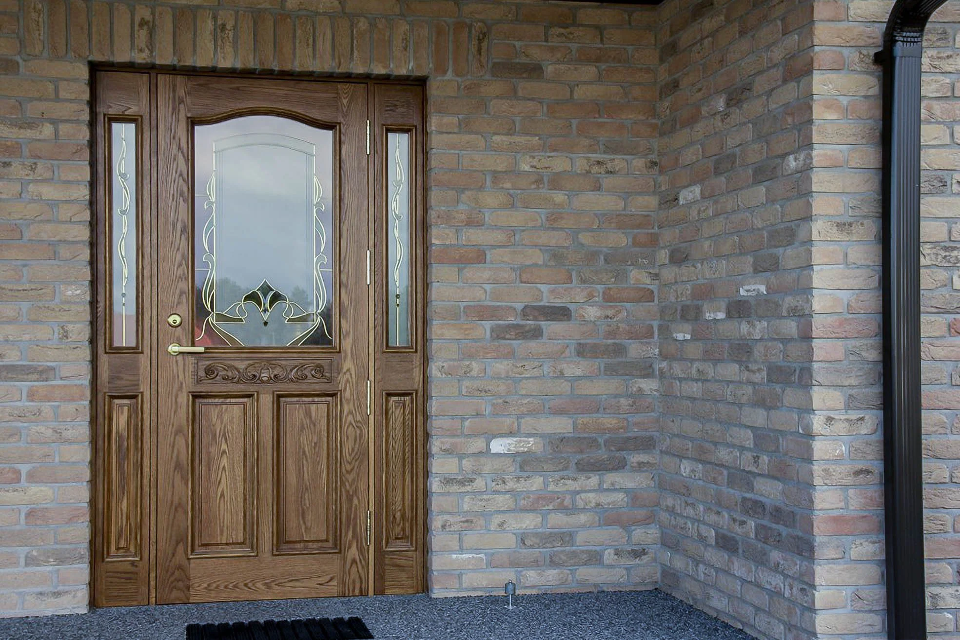 Puidust välisuks dekoratiivsete klaaspaneelidega, paigaldatud telliskiviseina sisse.