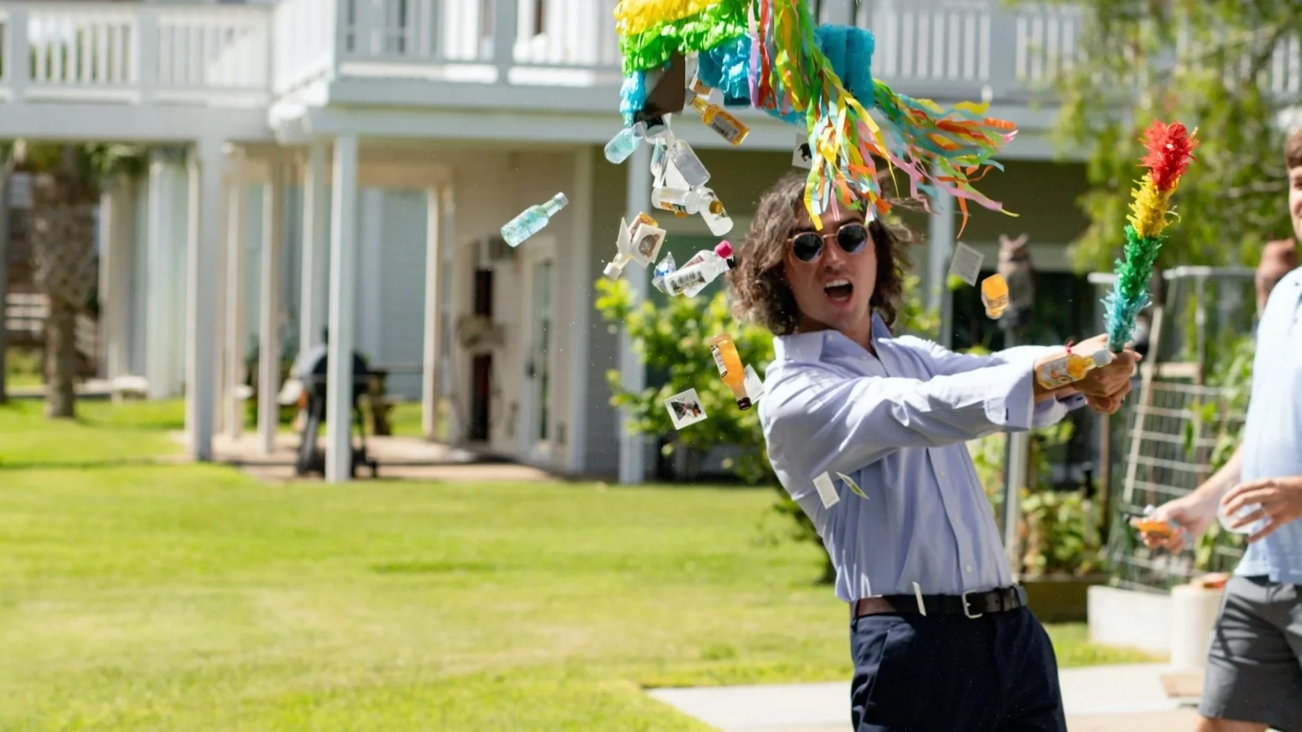 James McDougal, CFP® hitting a piñata on a sunny lawn with confetti falling down.