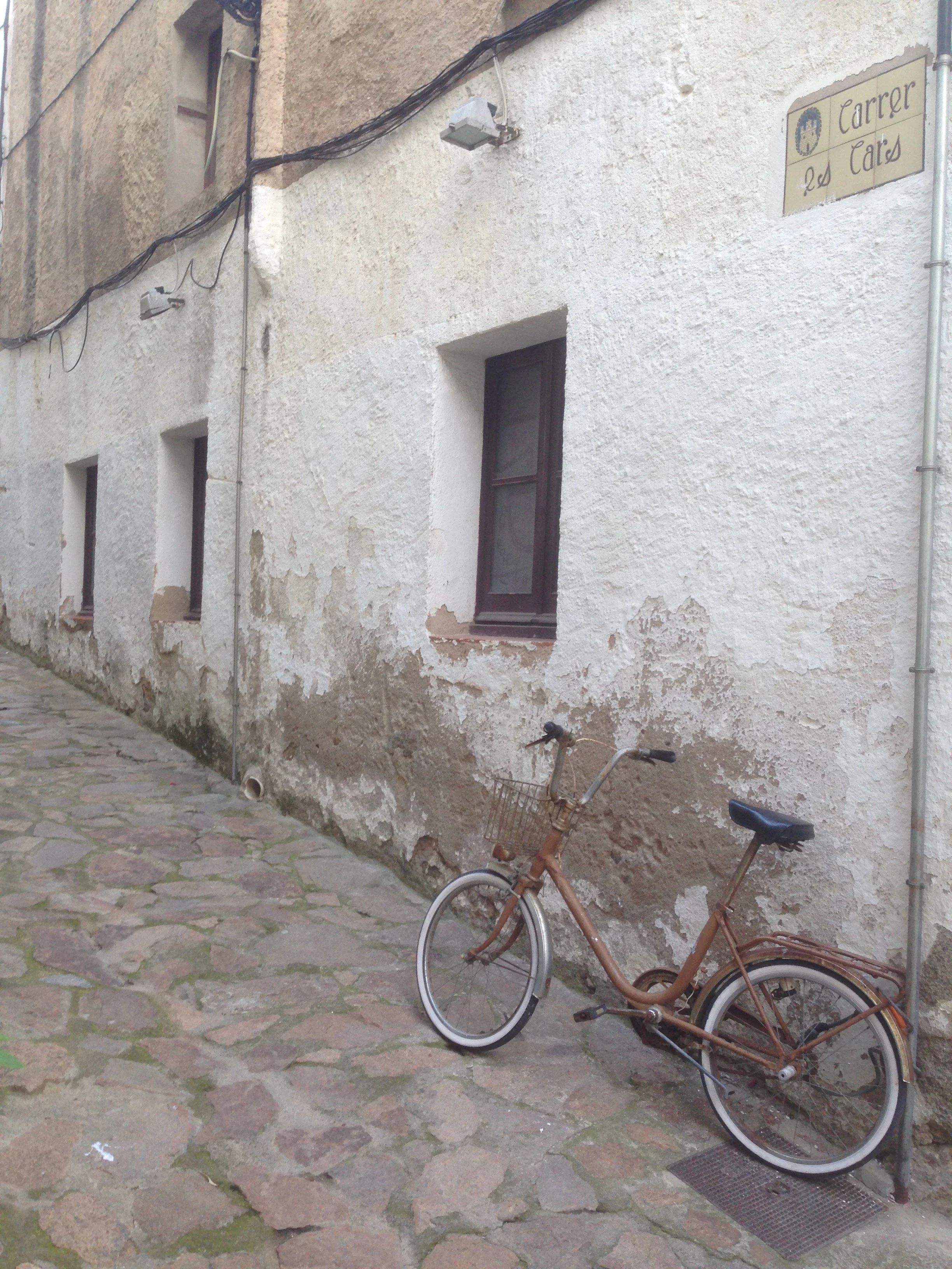 A solitary bicycle leaning against a wall in Tossa De Mar, Catalonia, Spain.