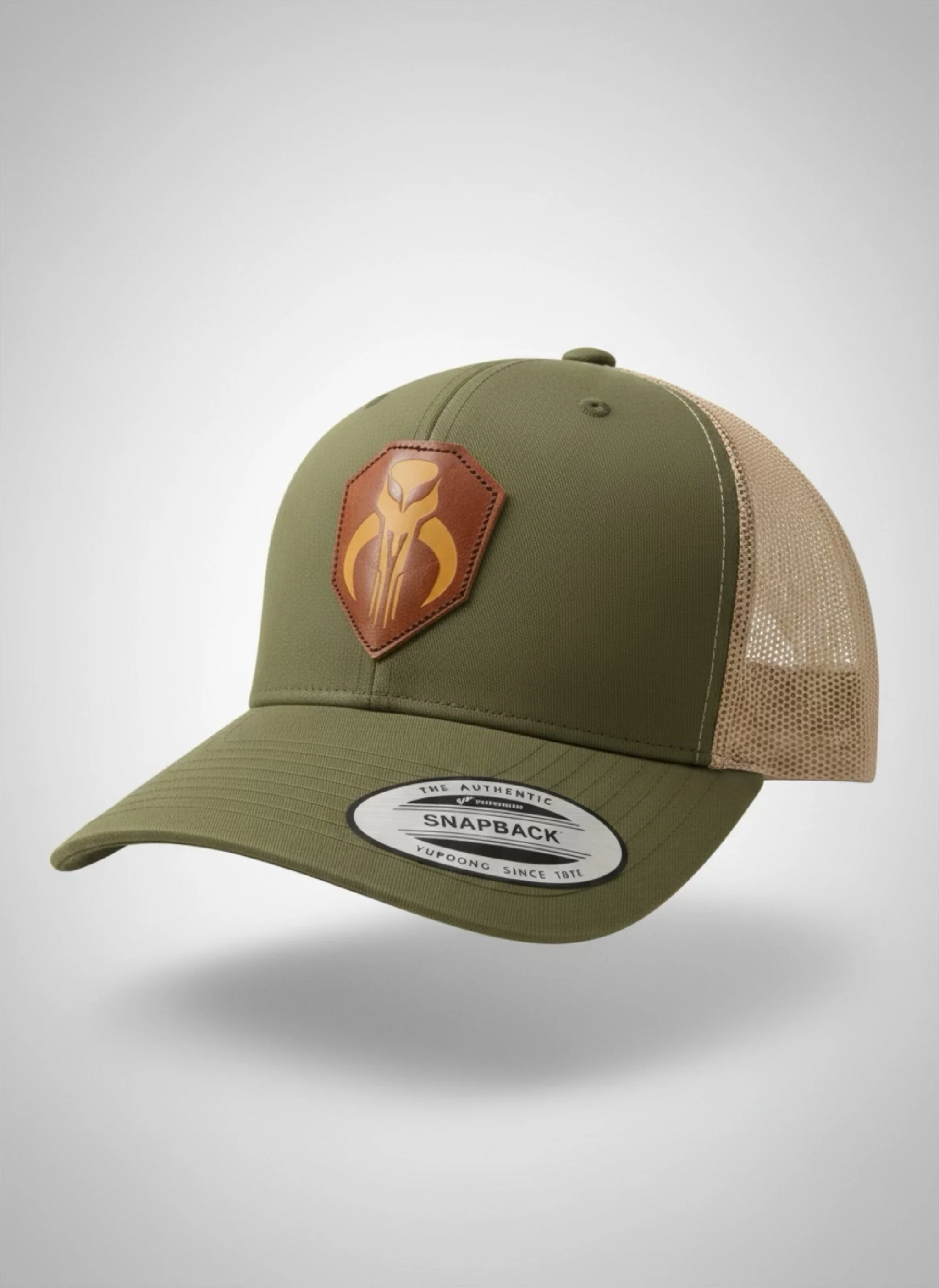 Olive green and tan trucker hat with a brown patch featuring a stylized snake emblem on the front and a sticker on the brim that reads "Snapback".