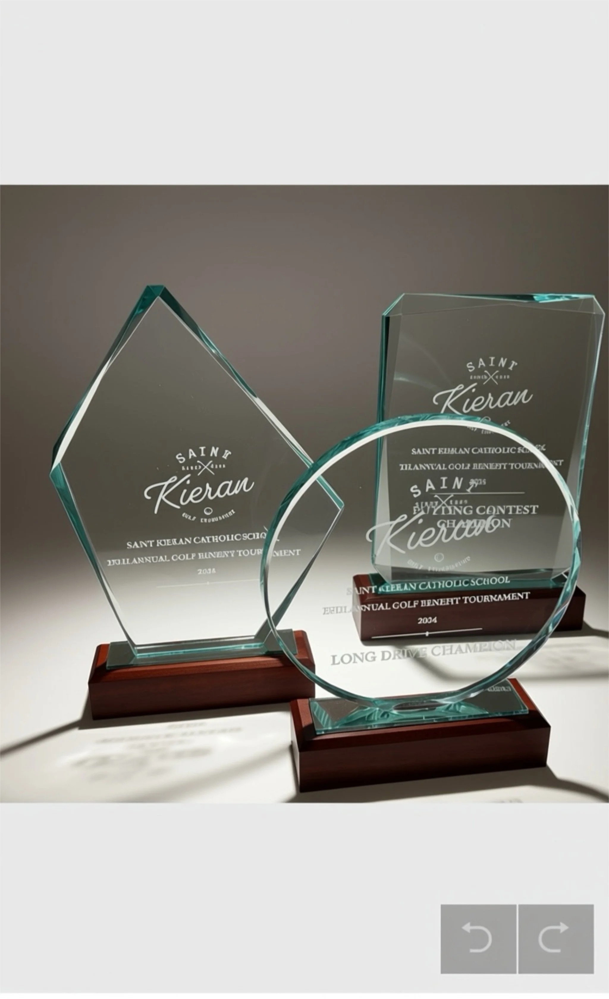 Three glass awards with wooden bases, engraved with 'Saint Kieran' for a golf tournament, displayed on a white surface.