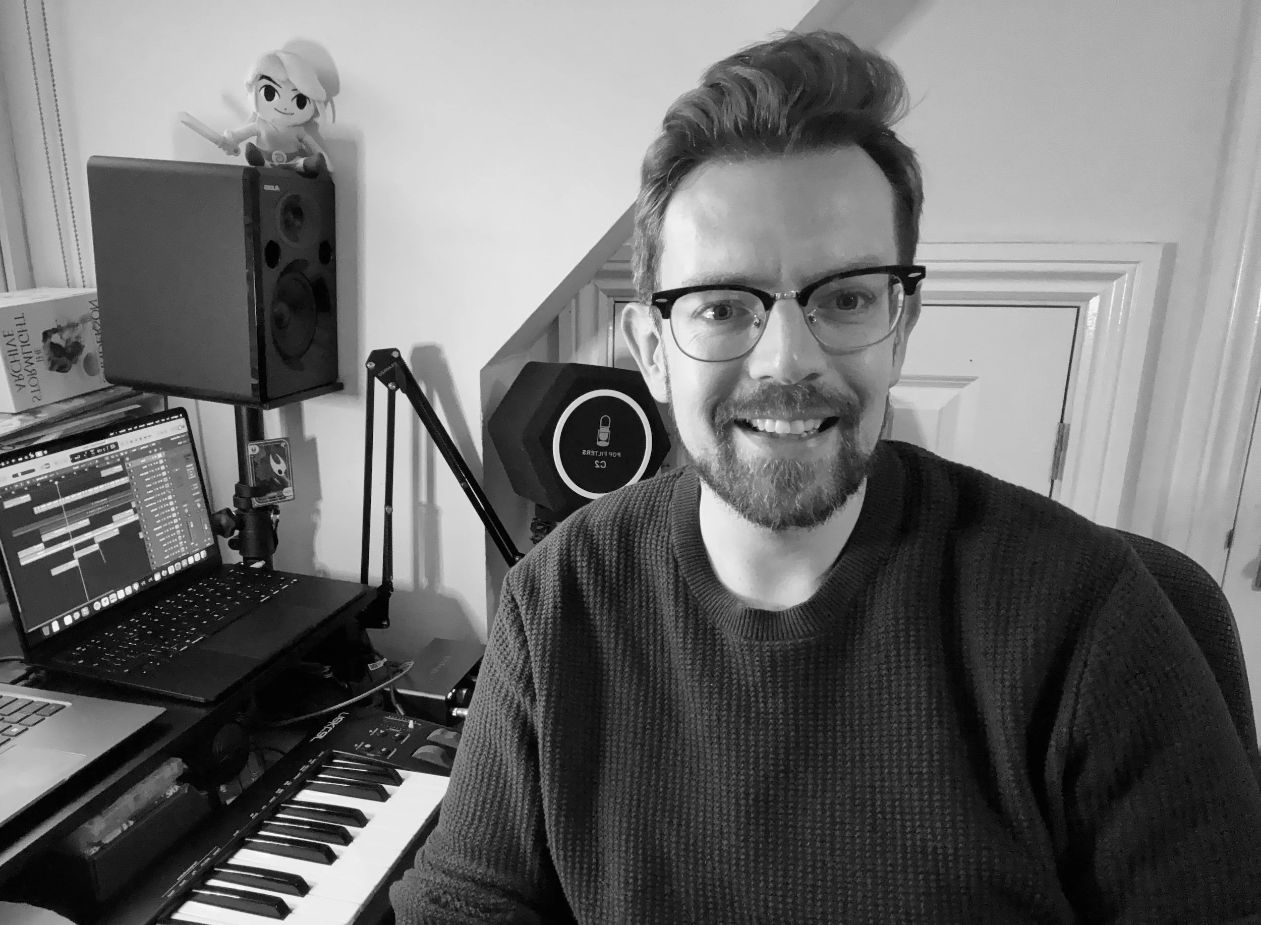 Portrait of composer sitting next to a keyboard, laptop and speakers