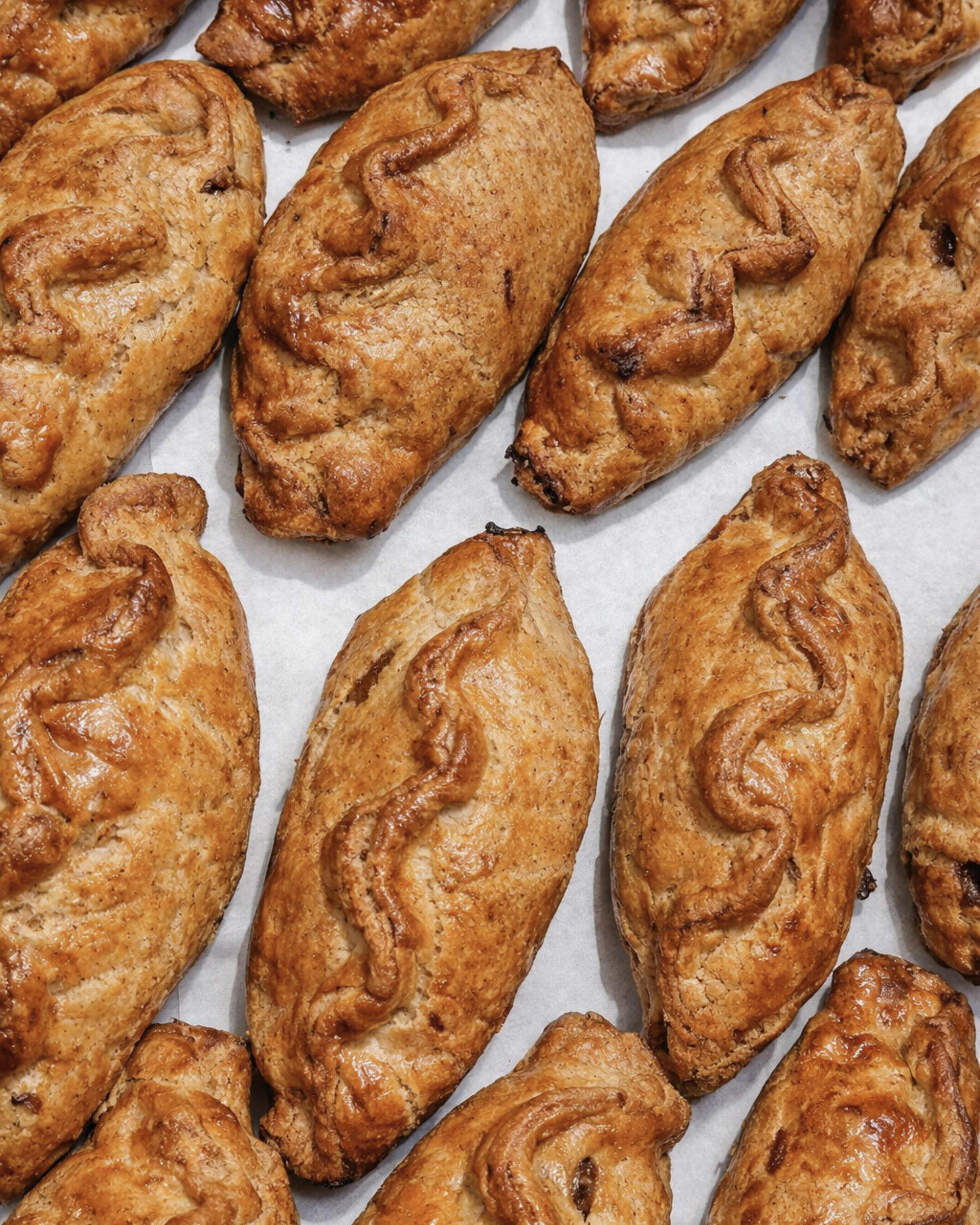 Close-up of baked sausage rolls on parchment paper.