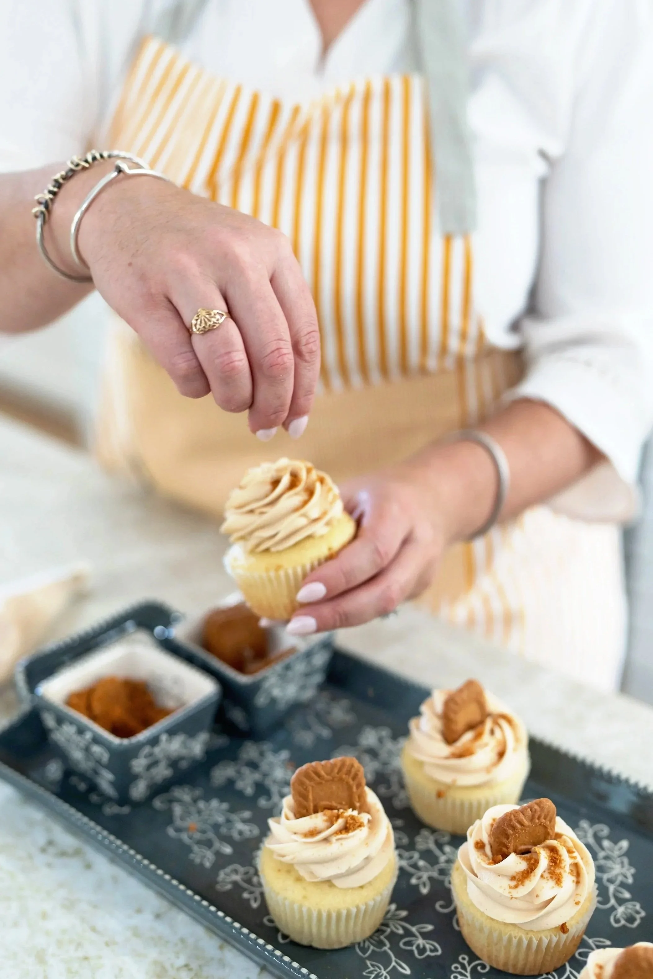 a hand sprinkling crumbs on a cupcake