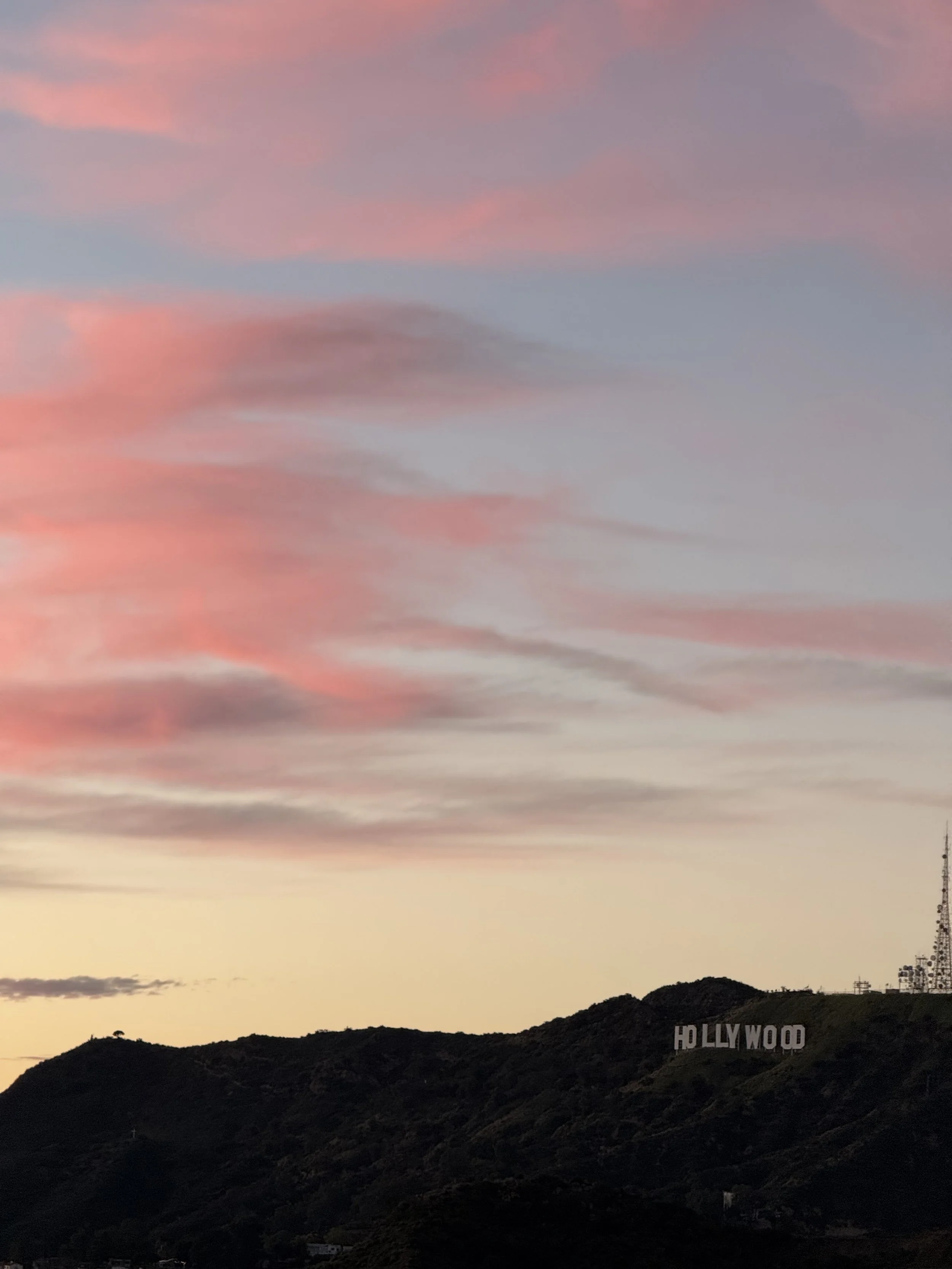 Sunset over the hills in Hollywood with the Hollywood sign and a TV antenna.