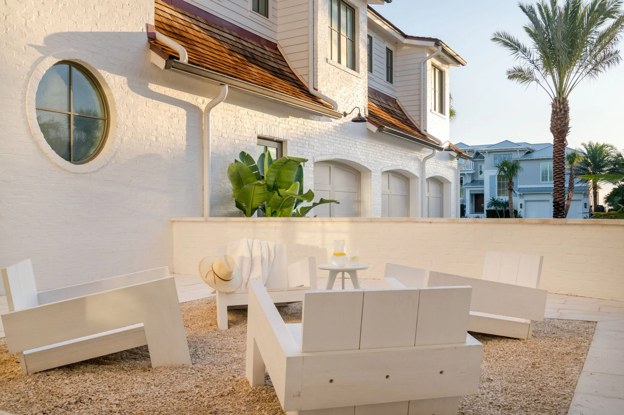 Intimate outdoor seating courtyard with crushed shell gravel, white brick walls, and coastal-inspired landscaping.