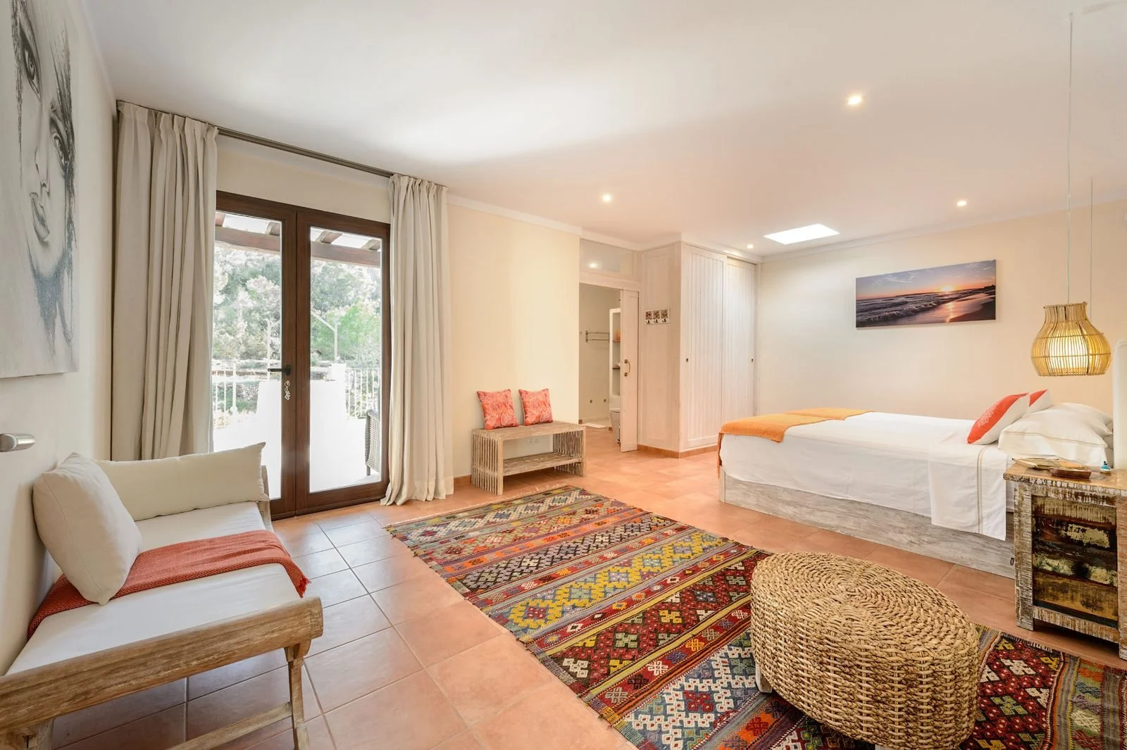 Example of a bright ensuite bedroom at our Ibiza retreat villa, with a sofa and terrace doors.