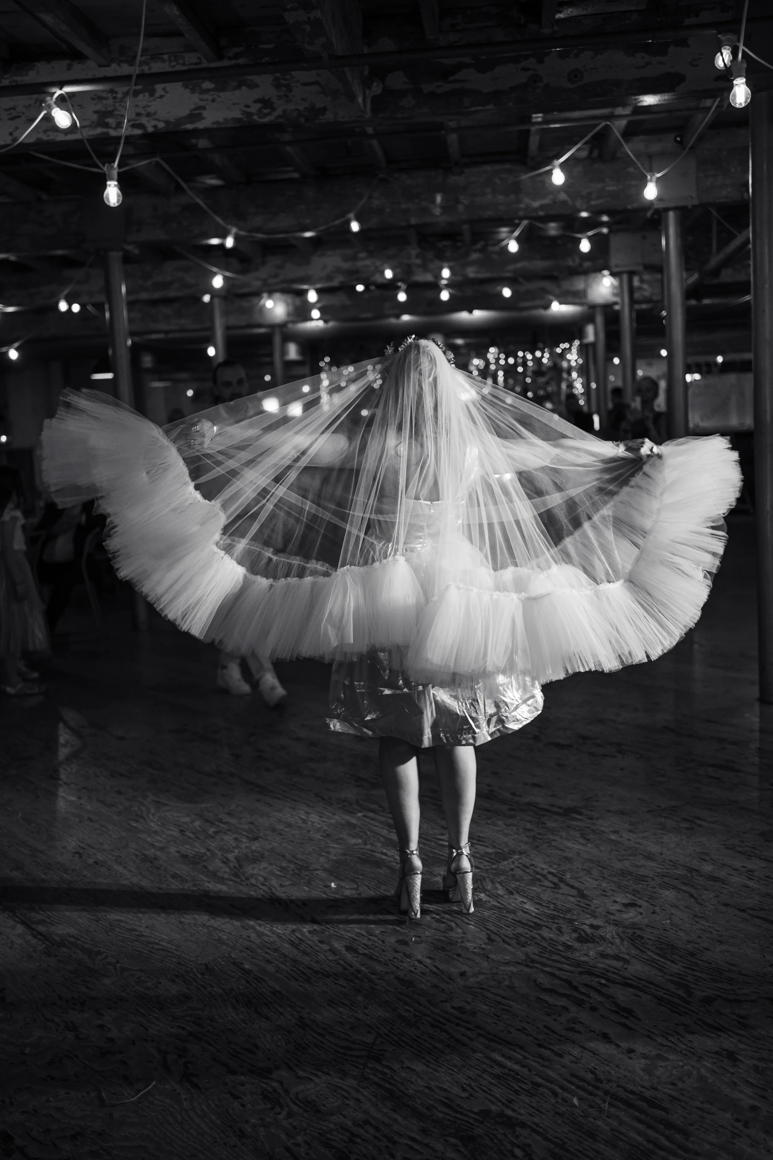 A bride in a wedding dress and veil dancing with her arms outstretched at Holmes Mill