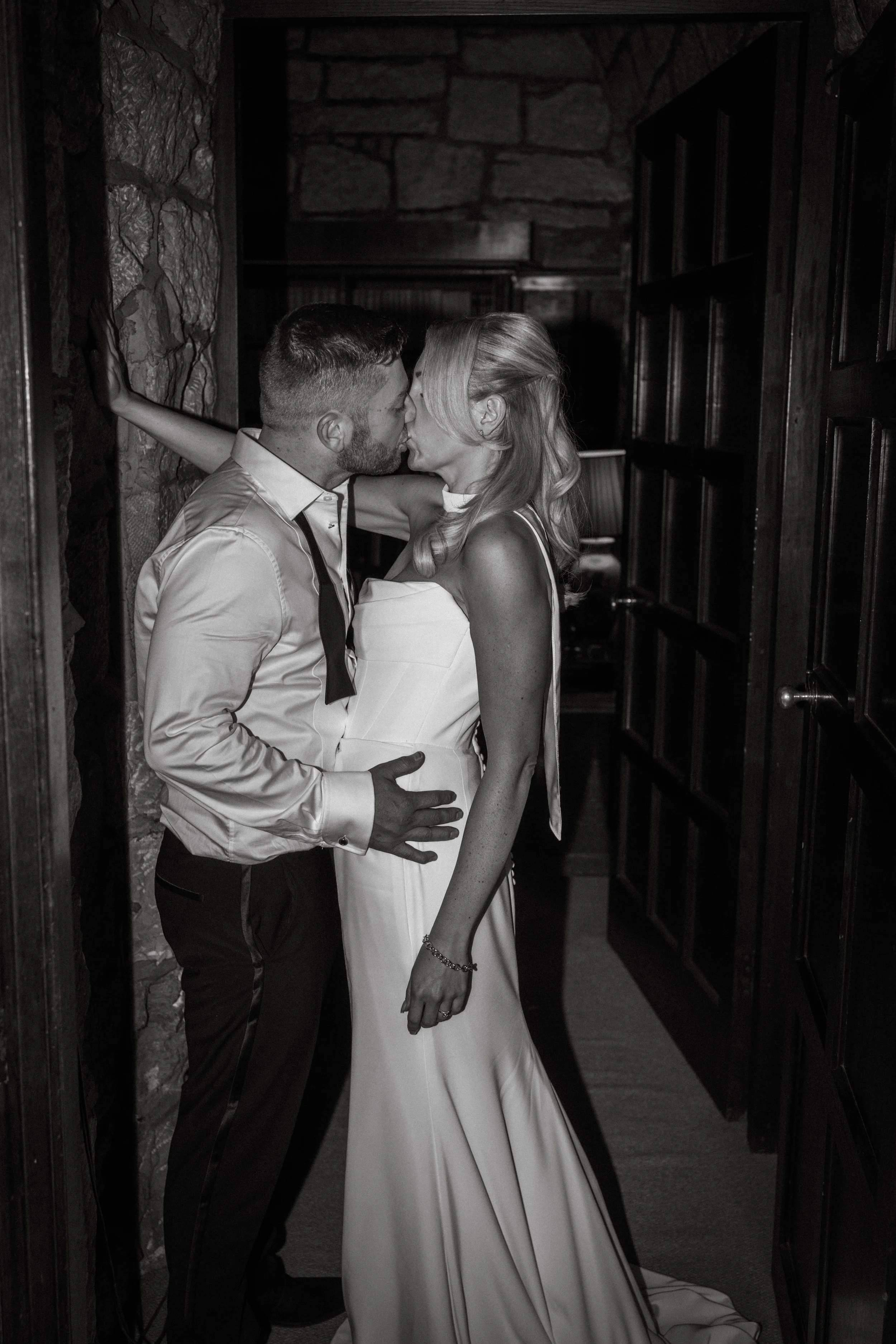 A black and white photograph of a couple kissing in an intimate moment at Askham Hall