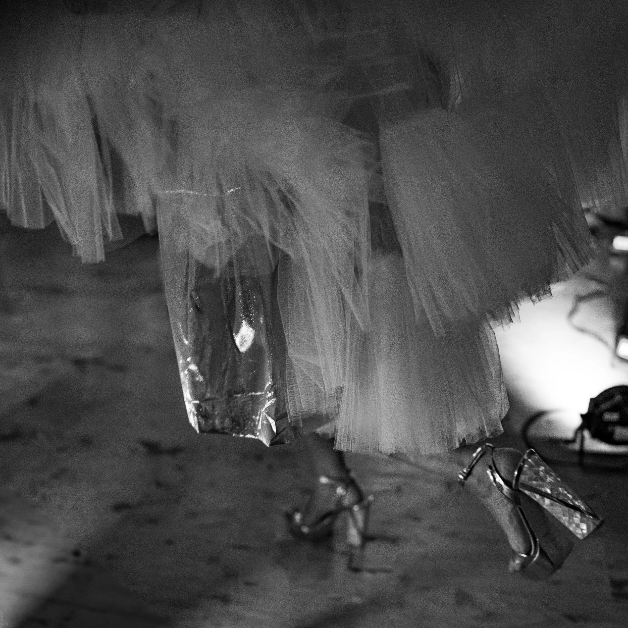 A close-up of a dress with a tulle skirt and high-heeled shoes on a wooden floor at Holmes Mill