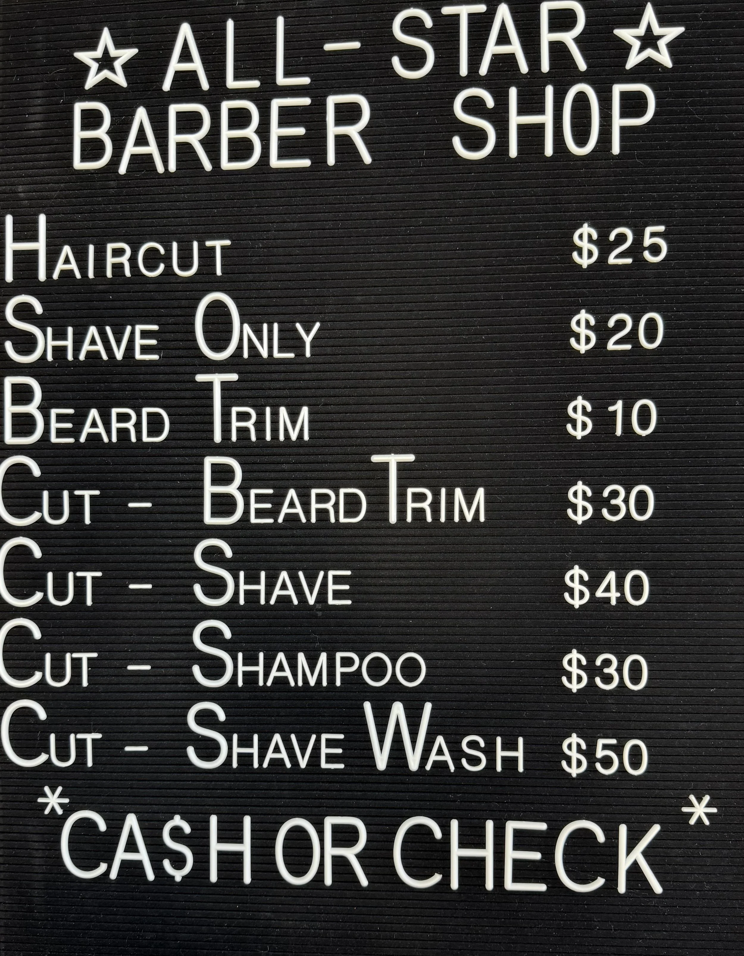 Black signboard with white neon text displaying services and prices for an all-star barber shop, including haircut, shave, beard trim, and shampoo, with cash or check payment option.