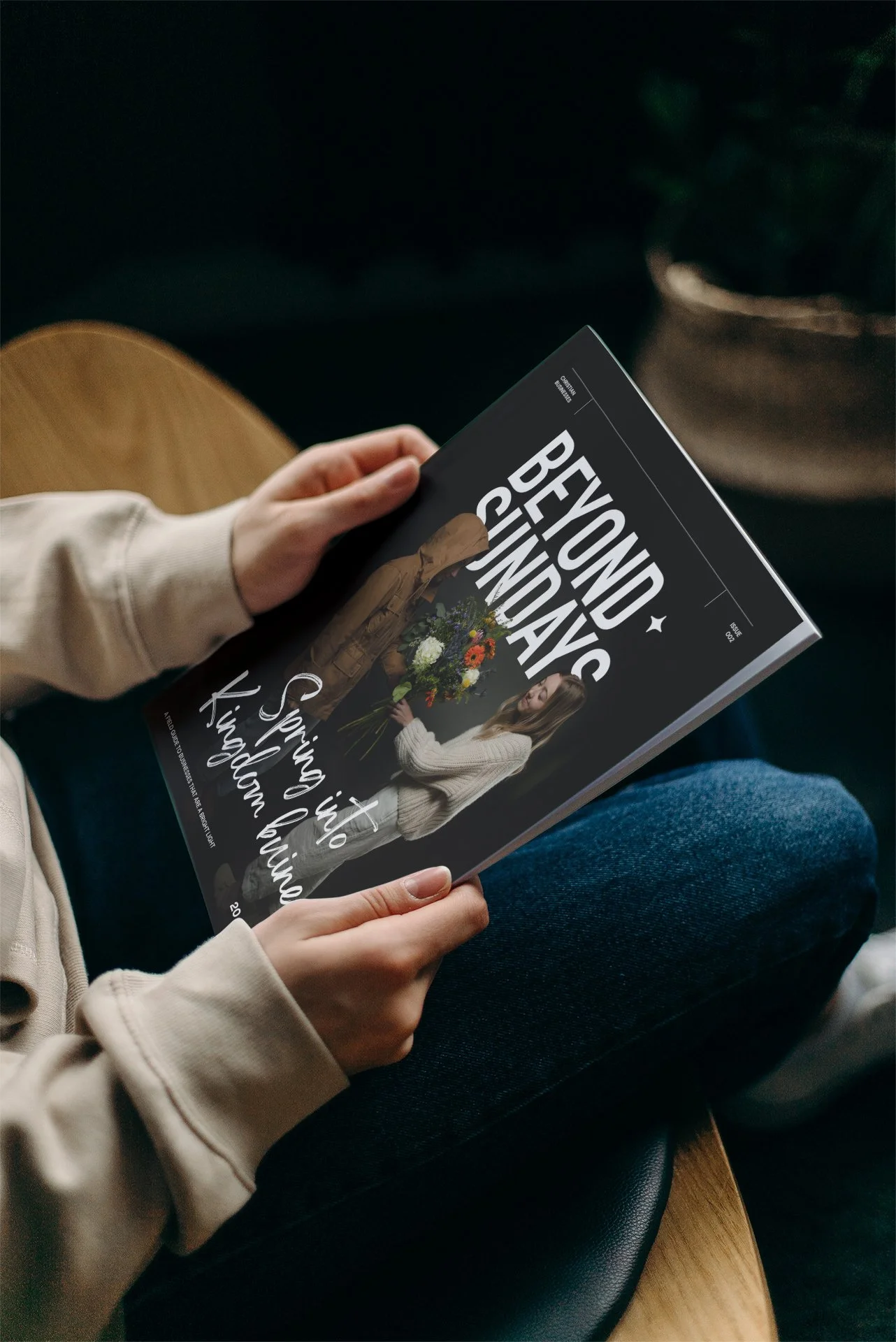 Person sitting on a chair reading a magazine titled 'Beyond Calendar' with a woman holding flowers on the cover.