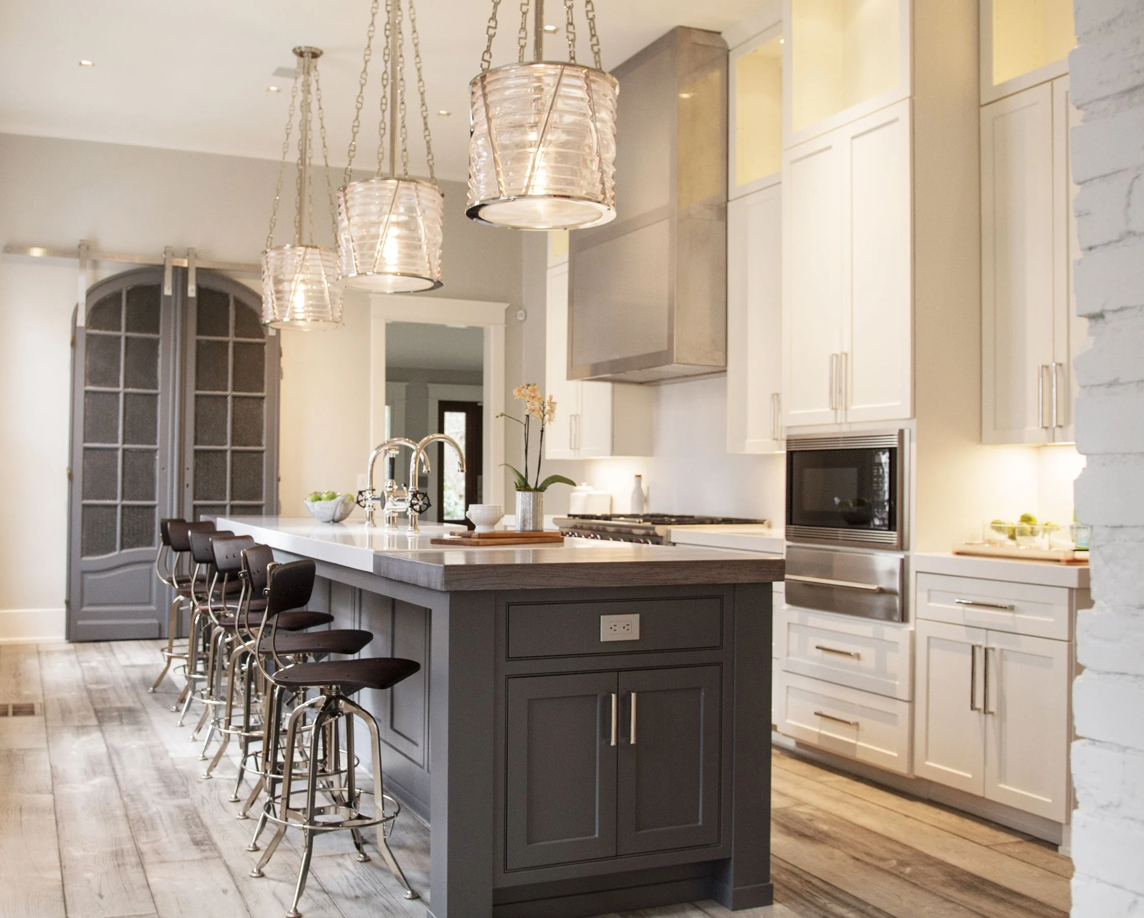 Custom kitchen with island seating, statement lighting, sliding barn door. Luxury home builder Nashville.